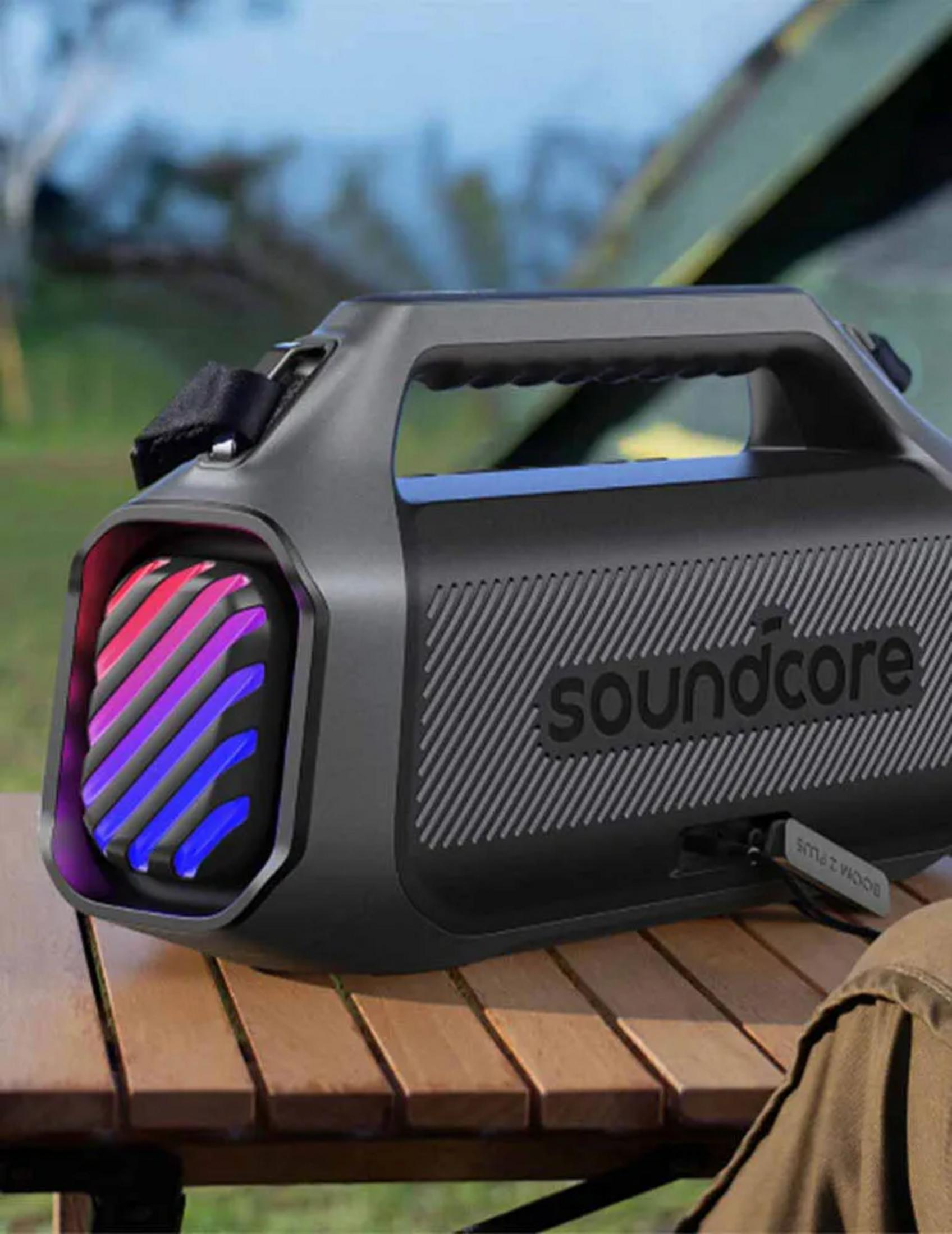 Altoparlante Bluetooth nero con luci rosse e blu su tavolo di legno.