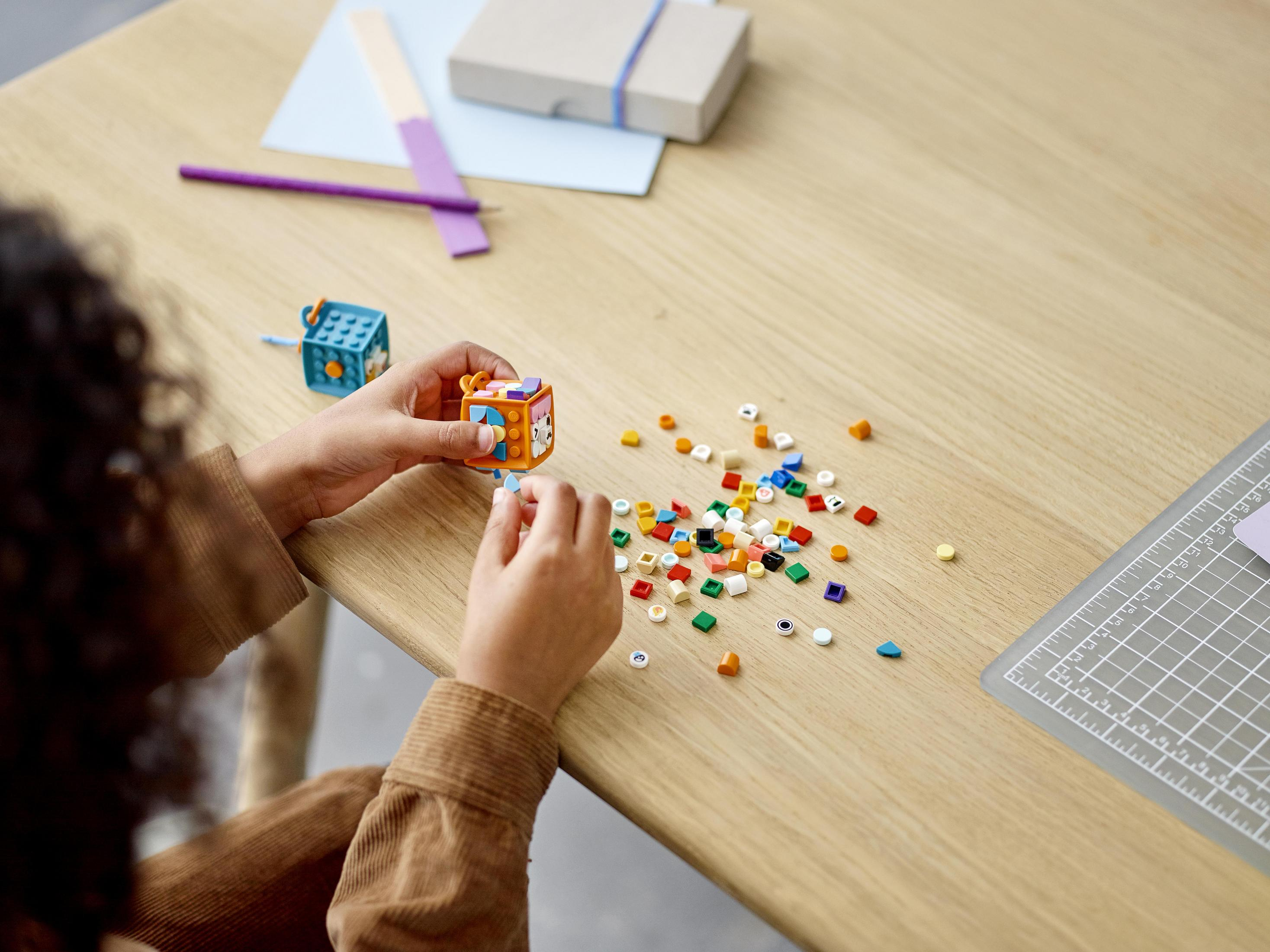 Un enfant construit avec des briques Lego colorées sur une table en bois.