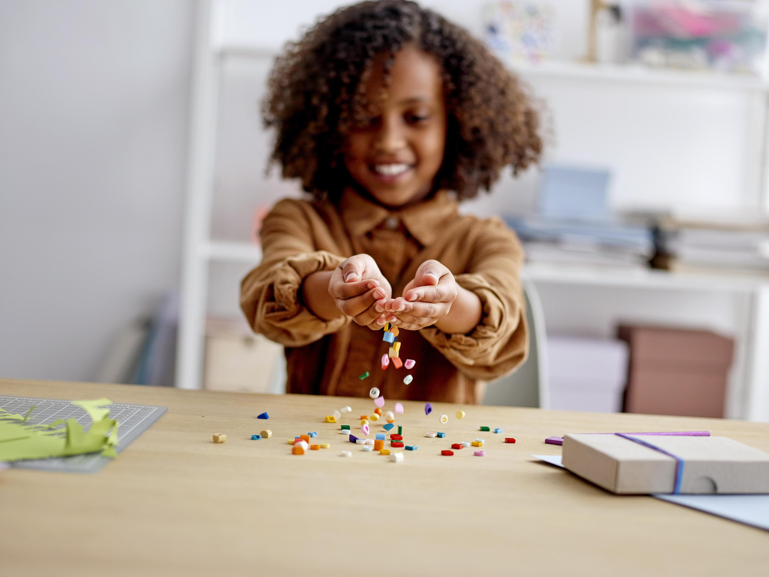 Une fille aux cheveux bouclés laisse tomber des blocs colorés.