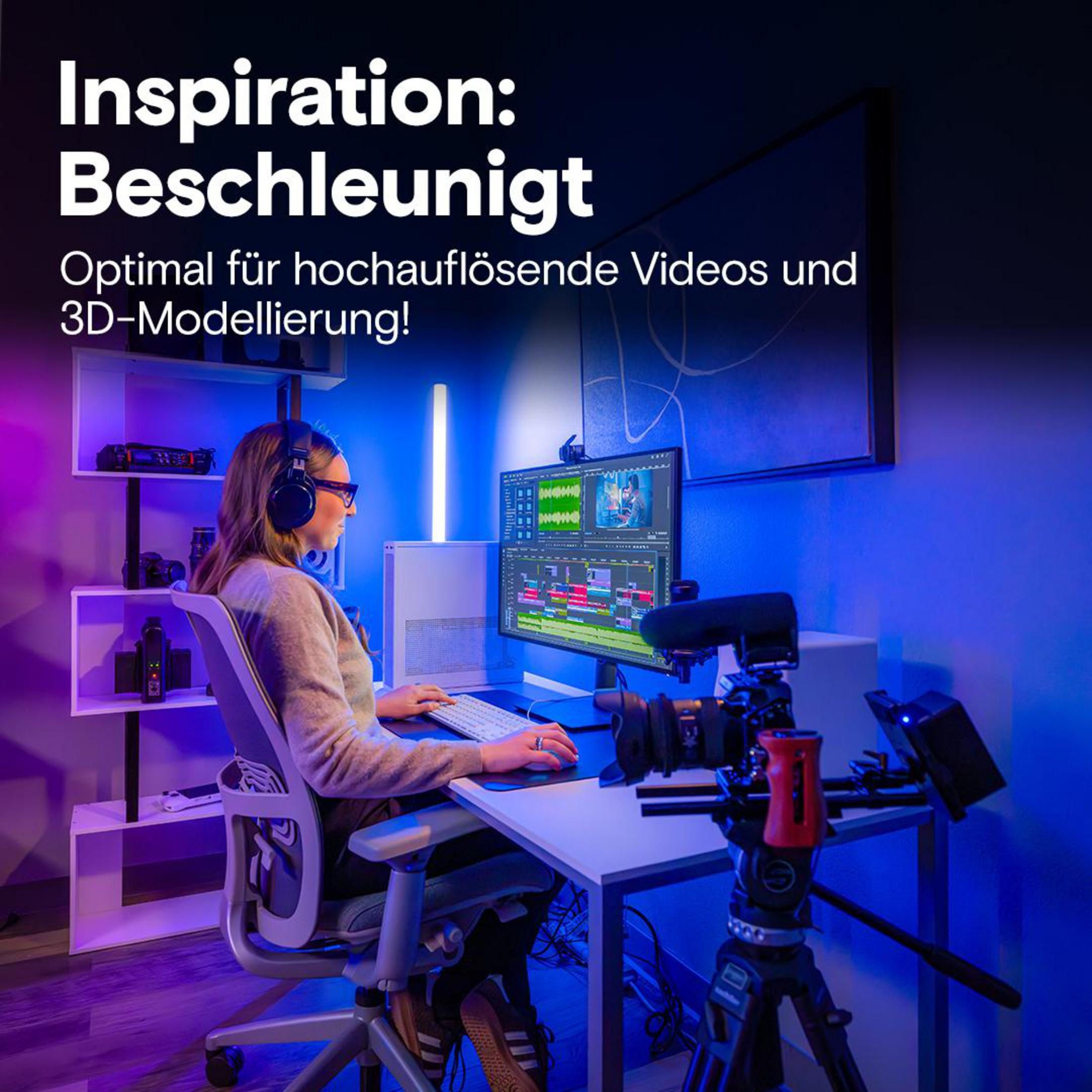 Donna alla scrivania edita video su computer, illuminata da luce blu.