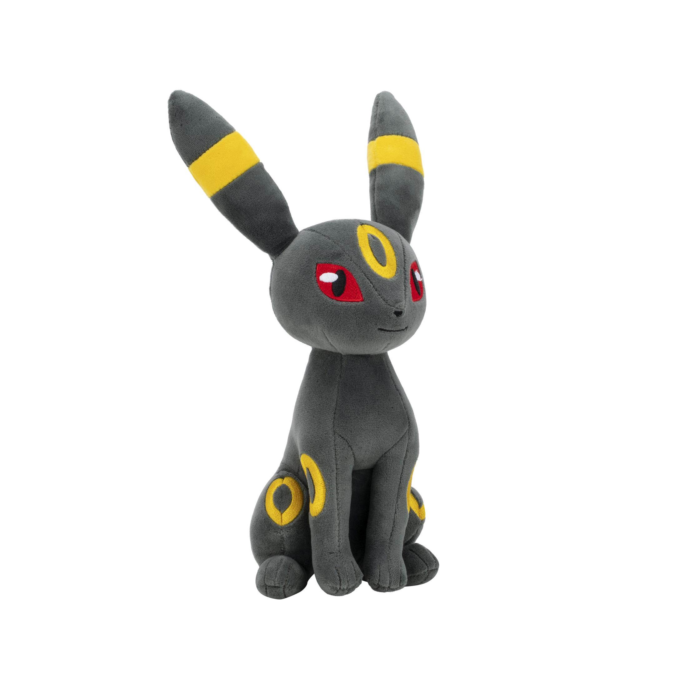 Un Umbreon en peluche gris avec des anneaux jaunes est assis.