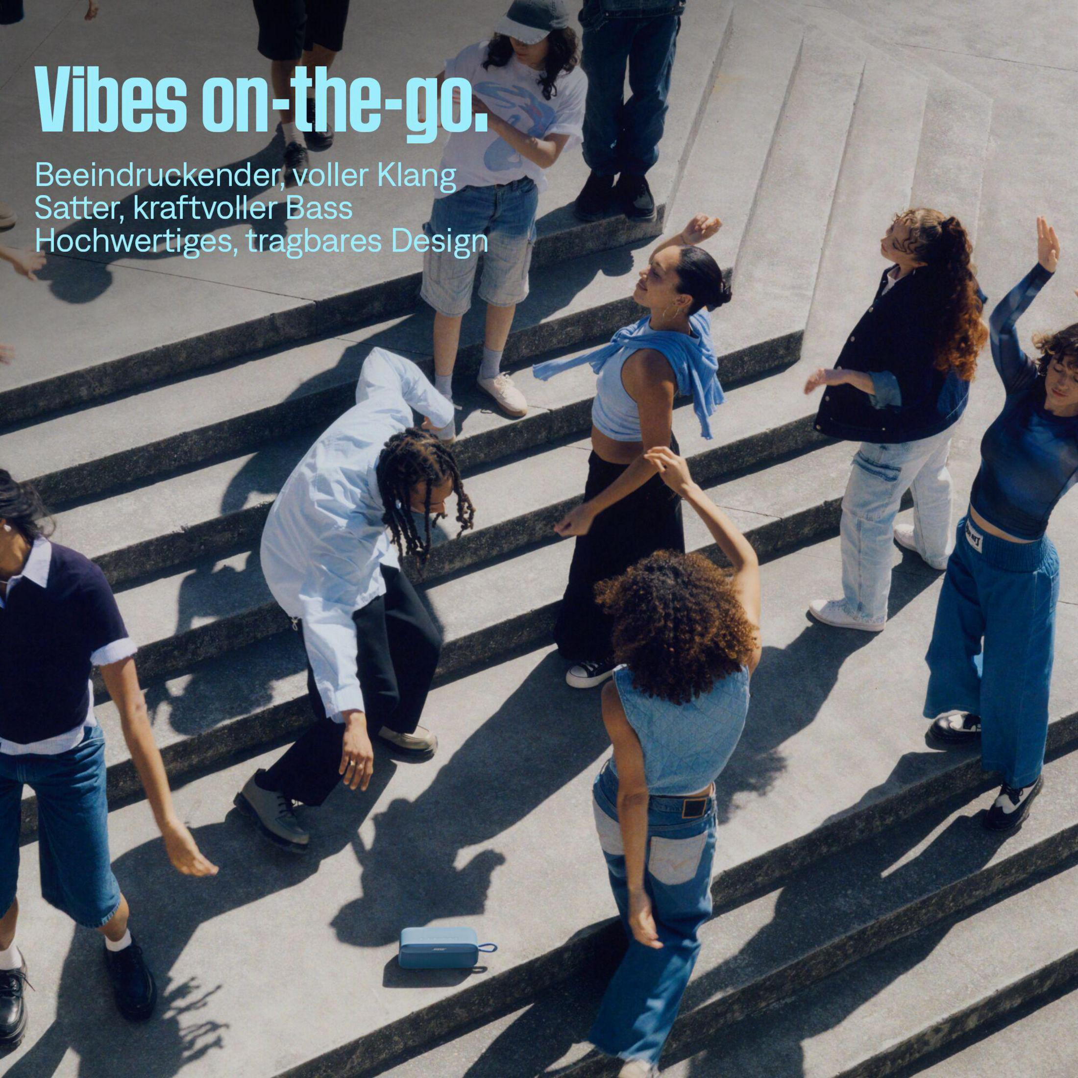 Un grupo de jóvenes baila en escaleras al son de la música de un altavoz azul.