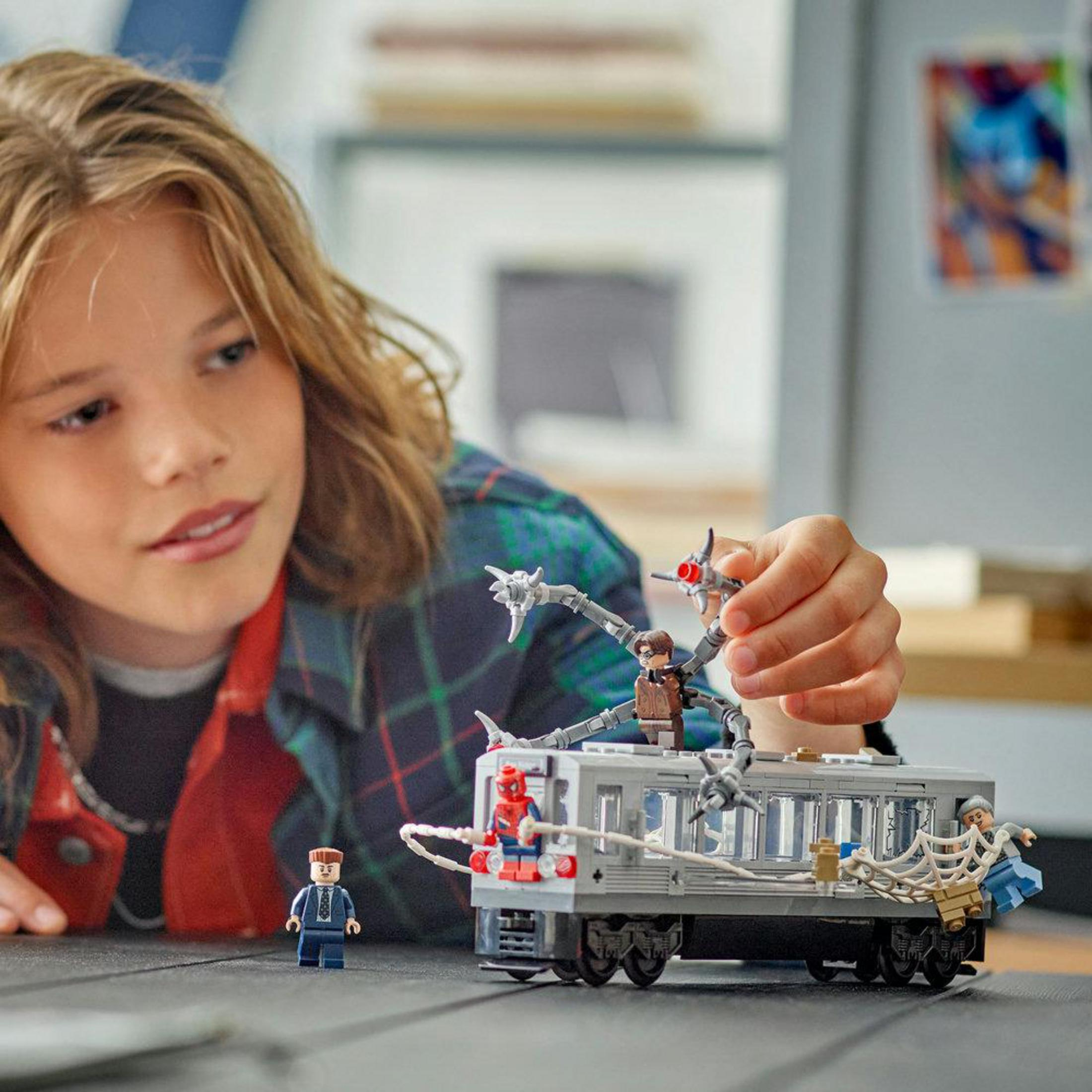 Un niño juega con un tren de Lego de Spider-Man con Doctor Octopus y otros personajes.