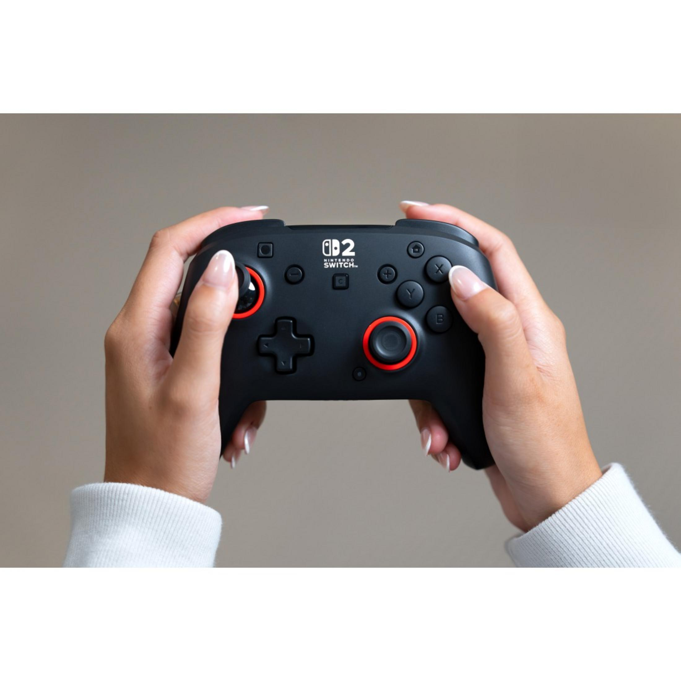 Schwarzer Controller für Nintendo Switch, gehalten von Händen mit roten Akzenten.