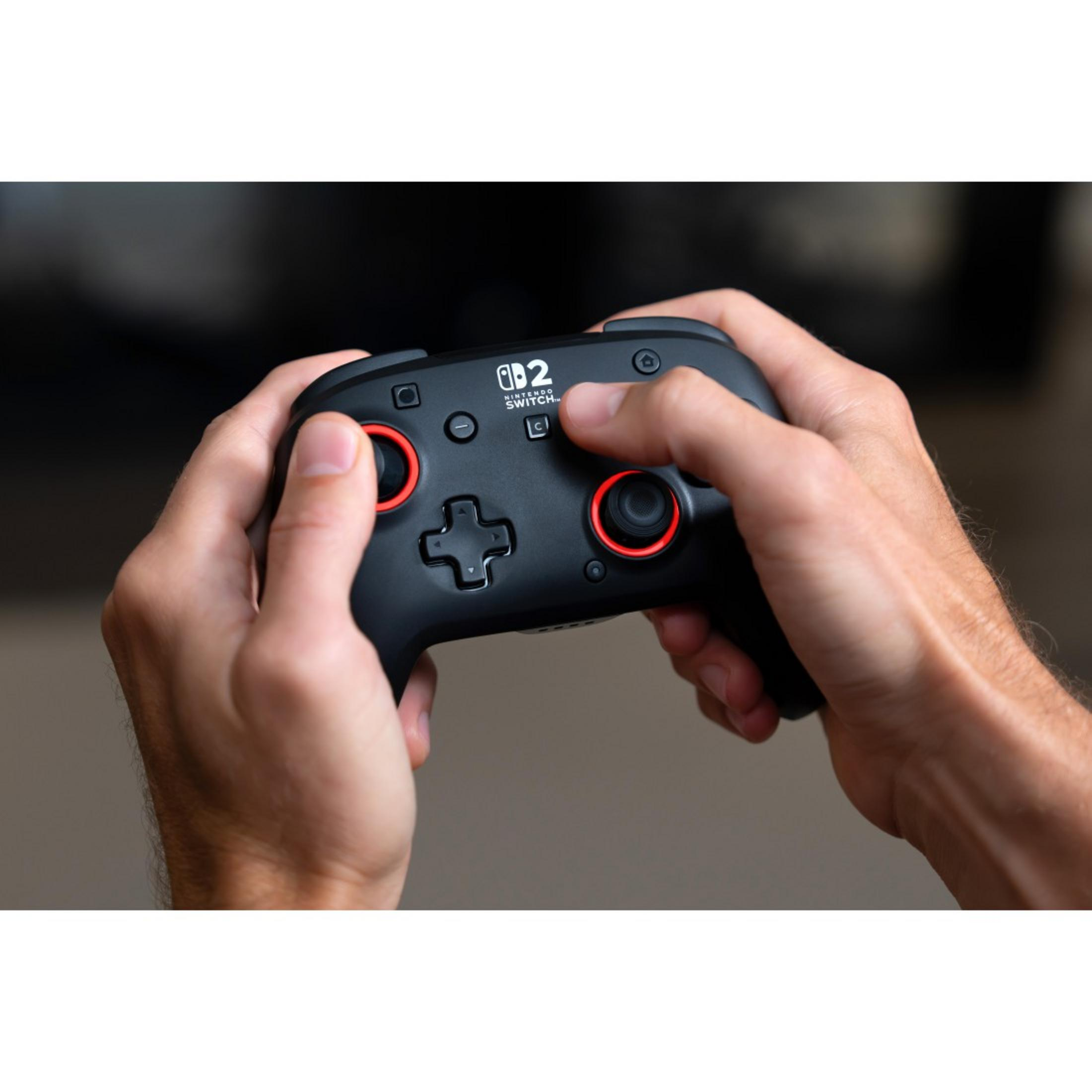 Zwei Hände halten einen schwarzen Nintendo Switch-Controller. Rote Ringe um die Joysticks.