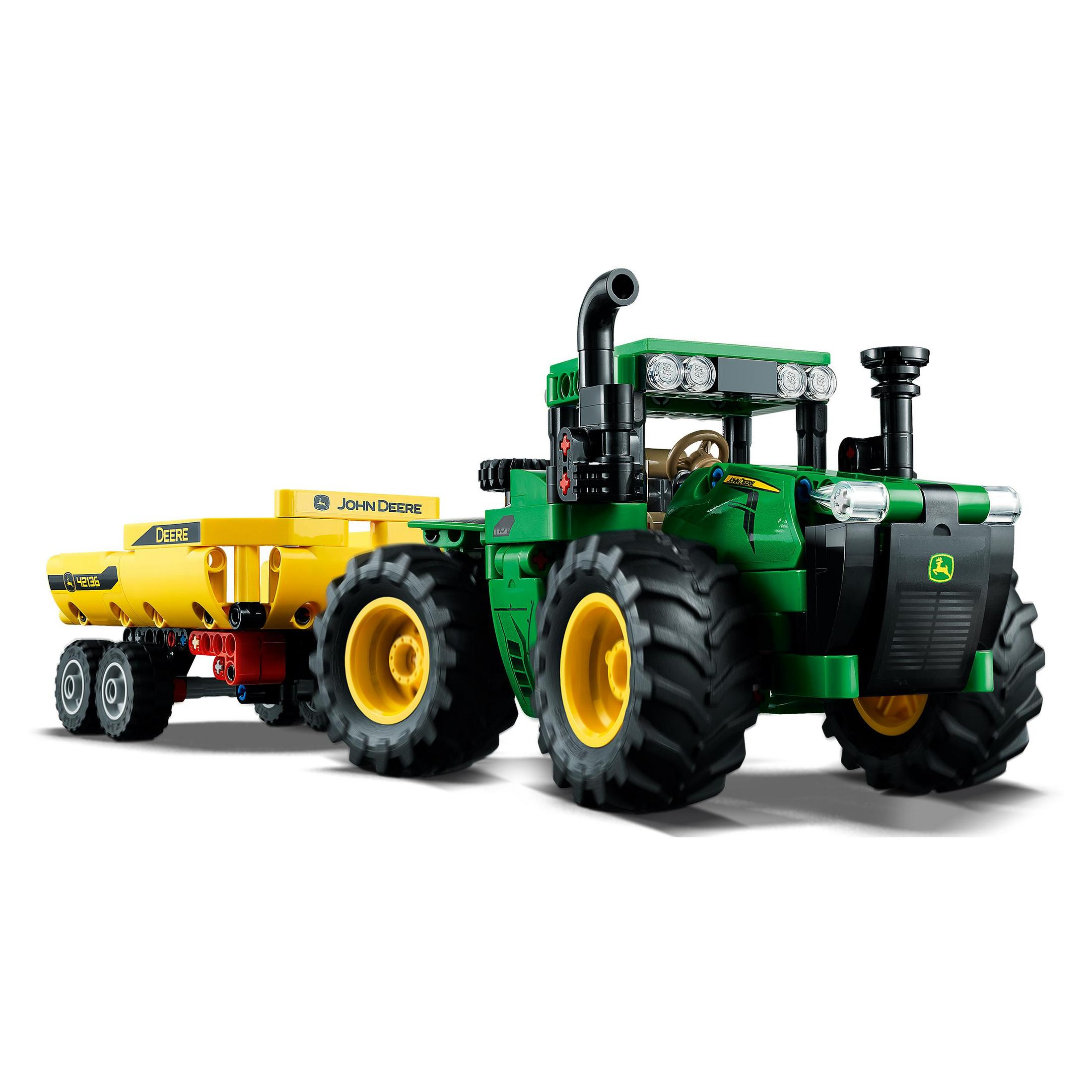 Grüner John Deere Traktor mit gelbem Anhänger und großen Reifen.