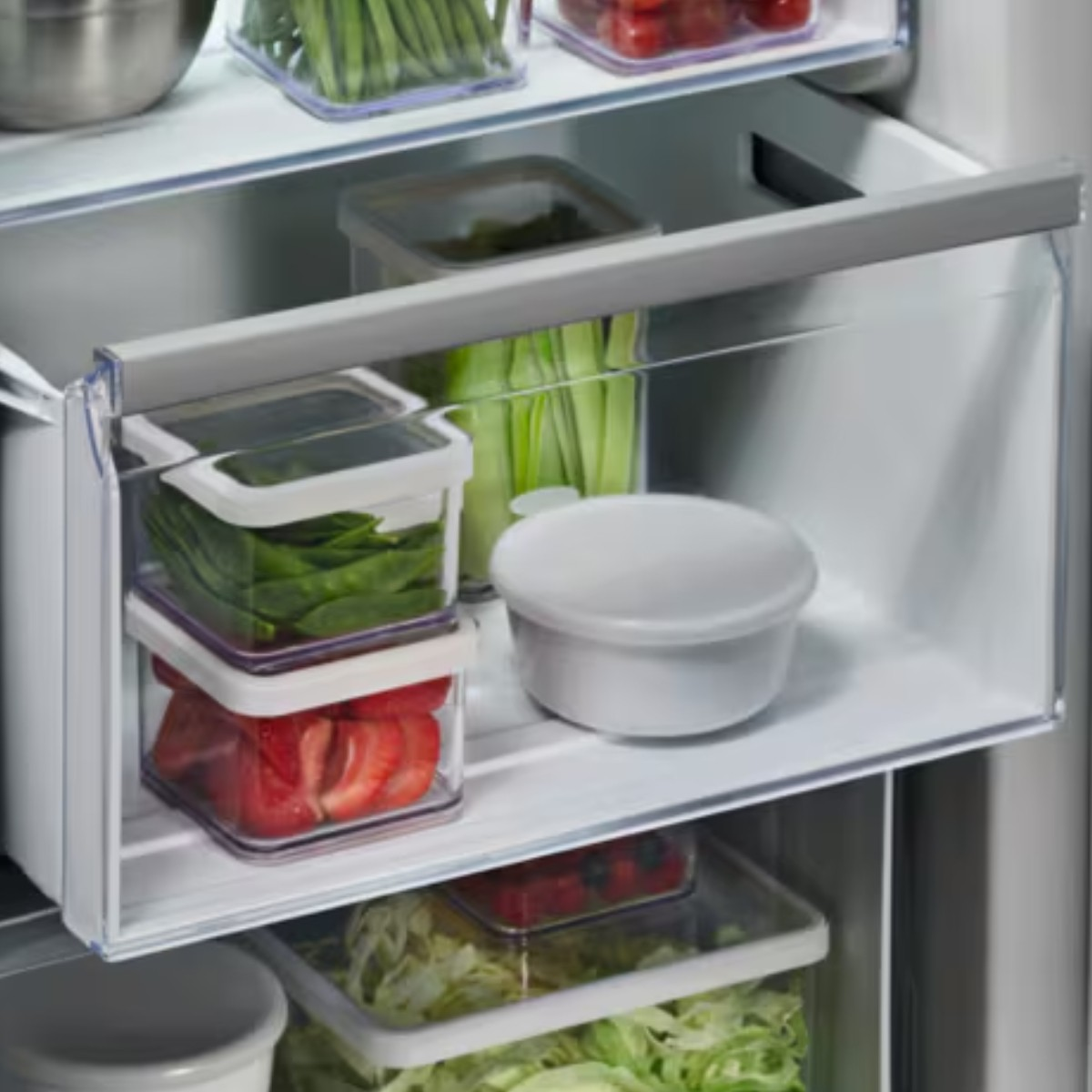Cajones de refrigerador llenos de frutas, verduras y recipientes.