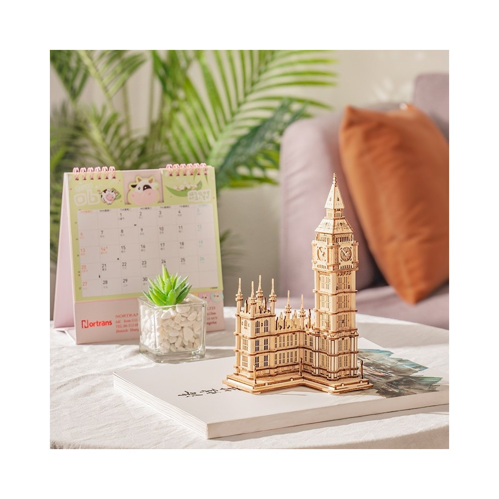 Big Ben'in ahşap modeli, takvim ve küçük bir bitkinin yanında duruyor.
