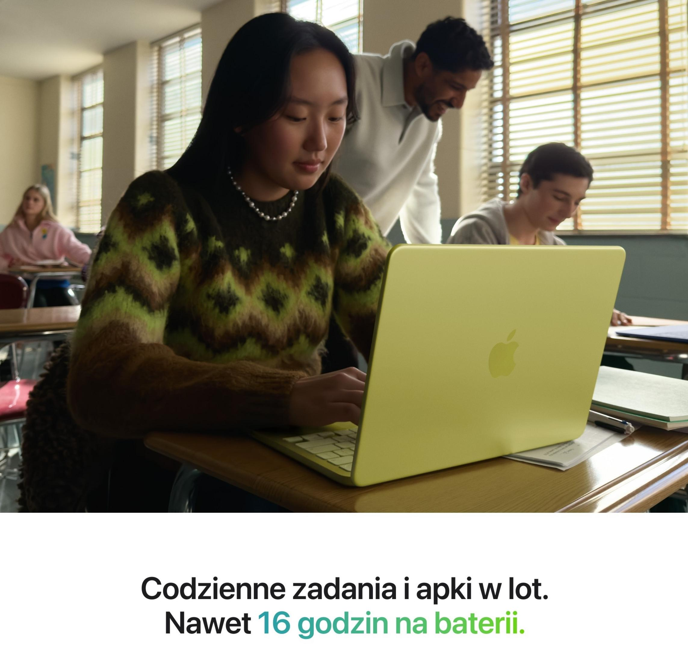 Schüler in einem Klassenzimmer benutzen gelbe Laptops, ein Lehrer steht dahinter.