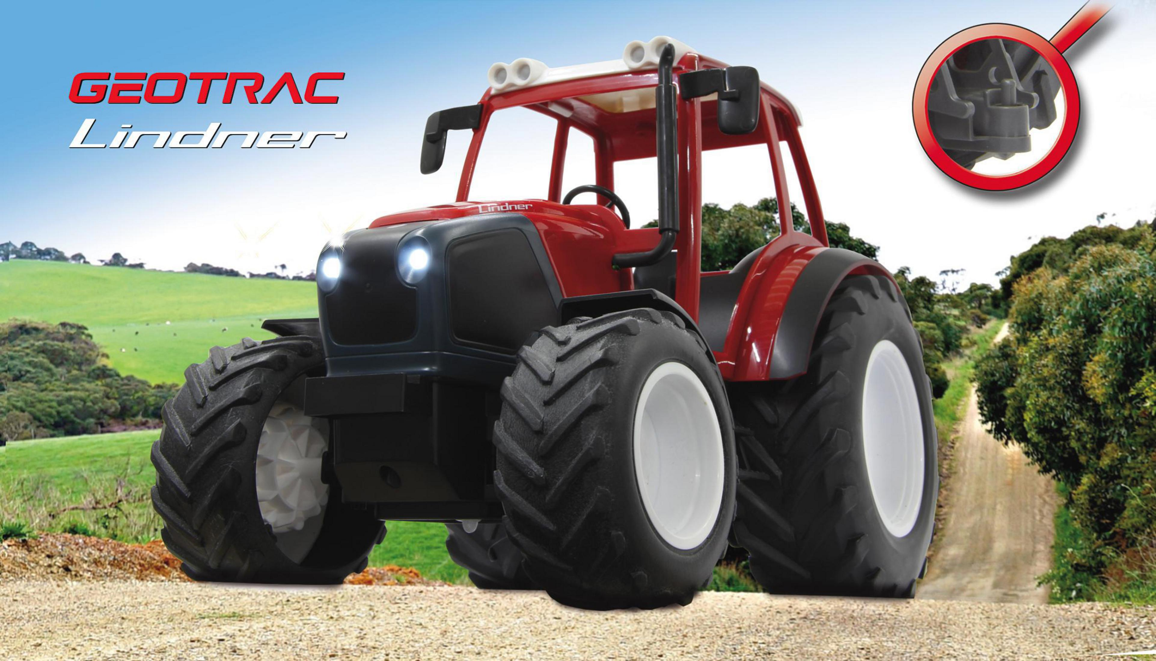 Ein roter Traktor mit großen Reifen steht auf einem Feldweg.
