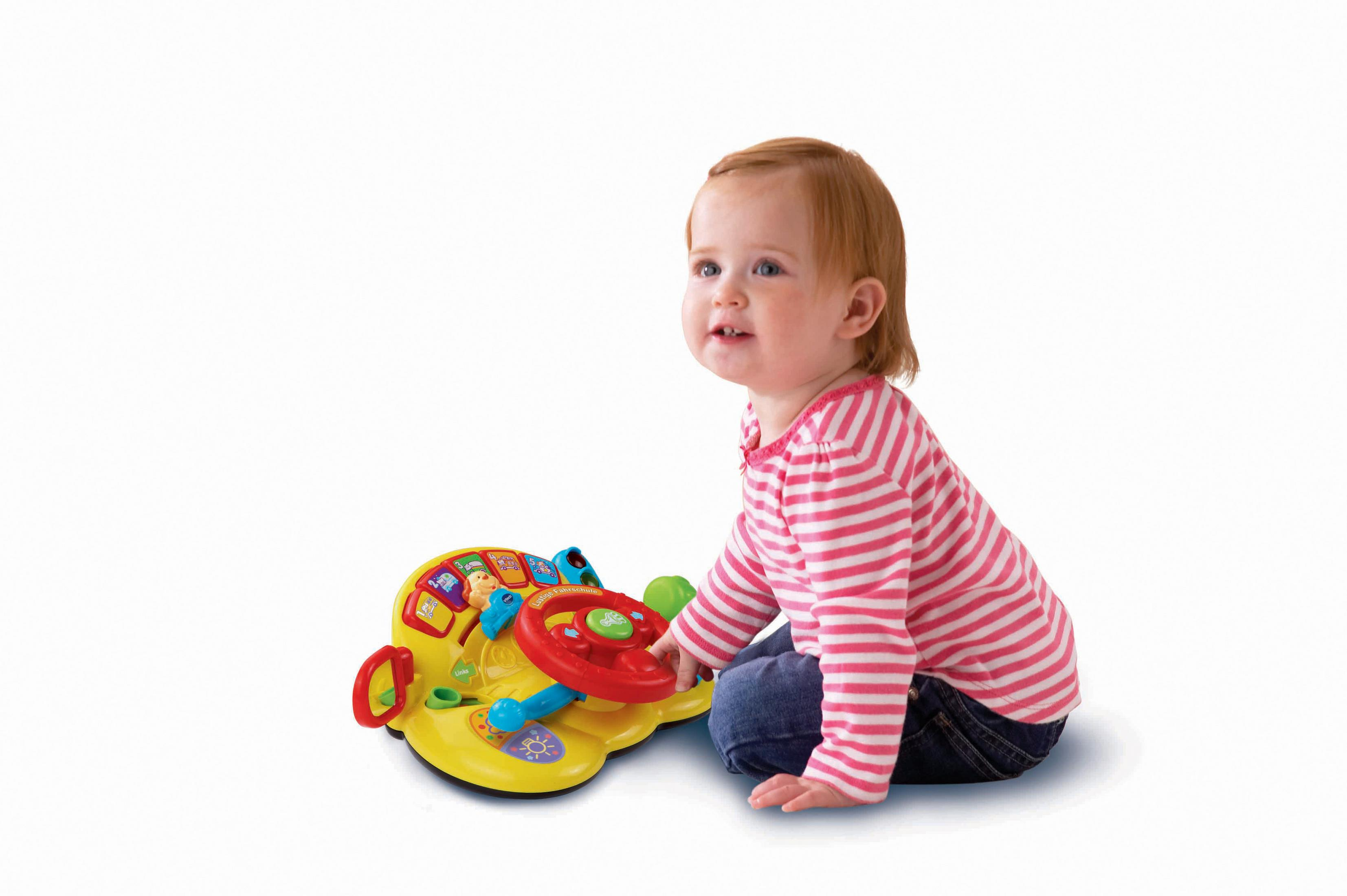 Ein kleines Mädchen mit rotem Haar spielt mit einem gelben Spielzeuglenkrad.