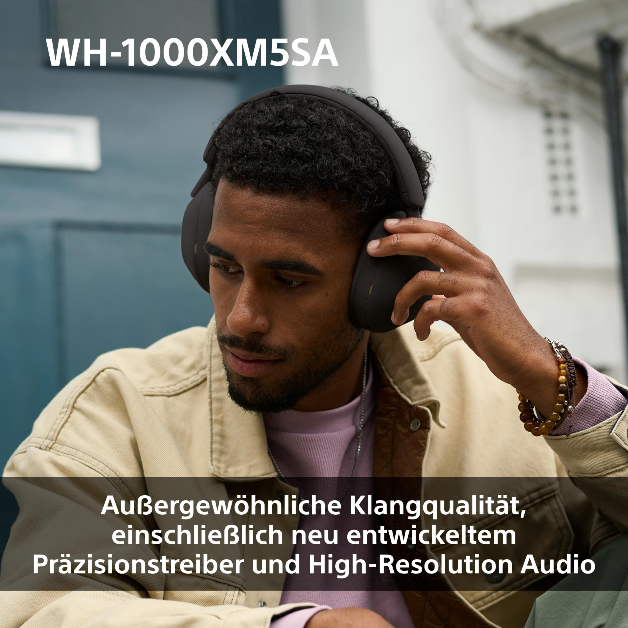 Homme portant un casque, vêtu d'une veste beige. Texte : WH-1000XM5SA