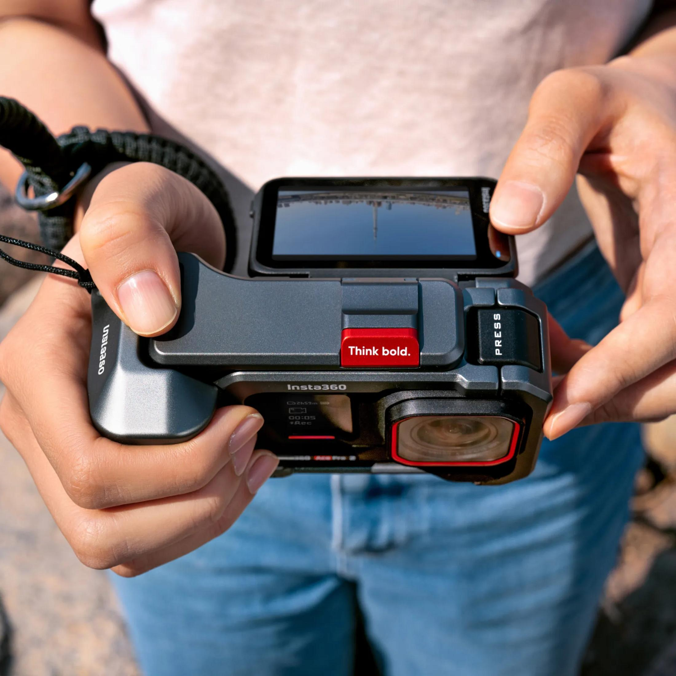 Person hält Insta360 Kamera mit rotem "Think bold."-Knopf und "PRESS"-Taste.