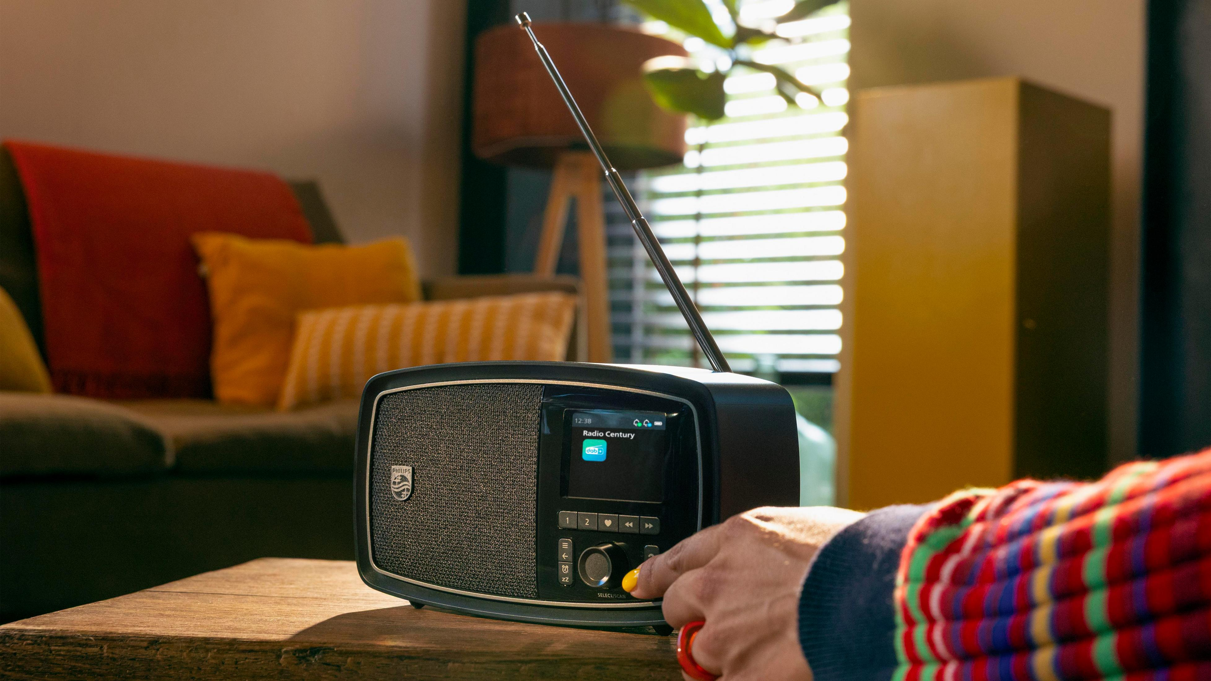 Une radio noire avec antenne est posée sur une table en bois.