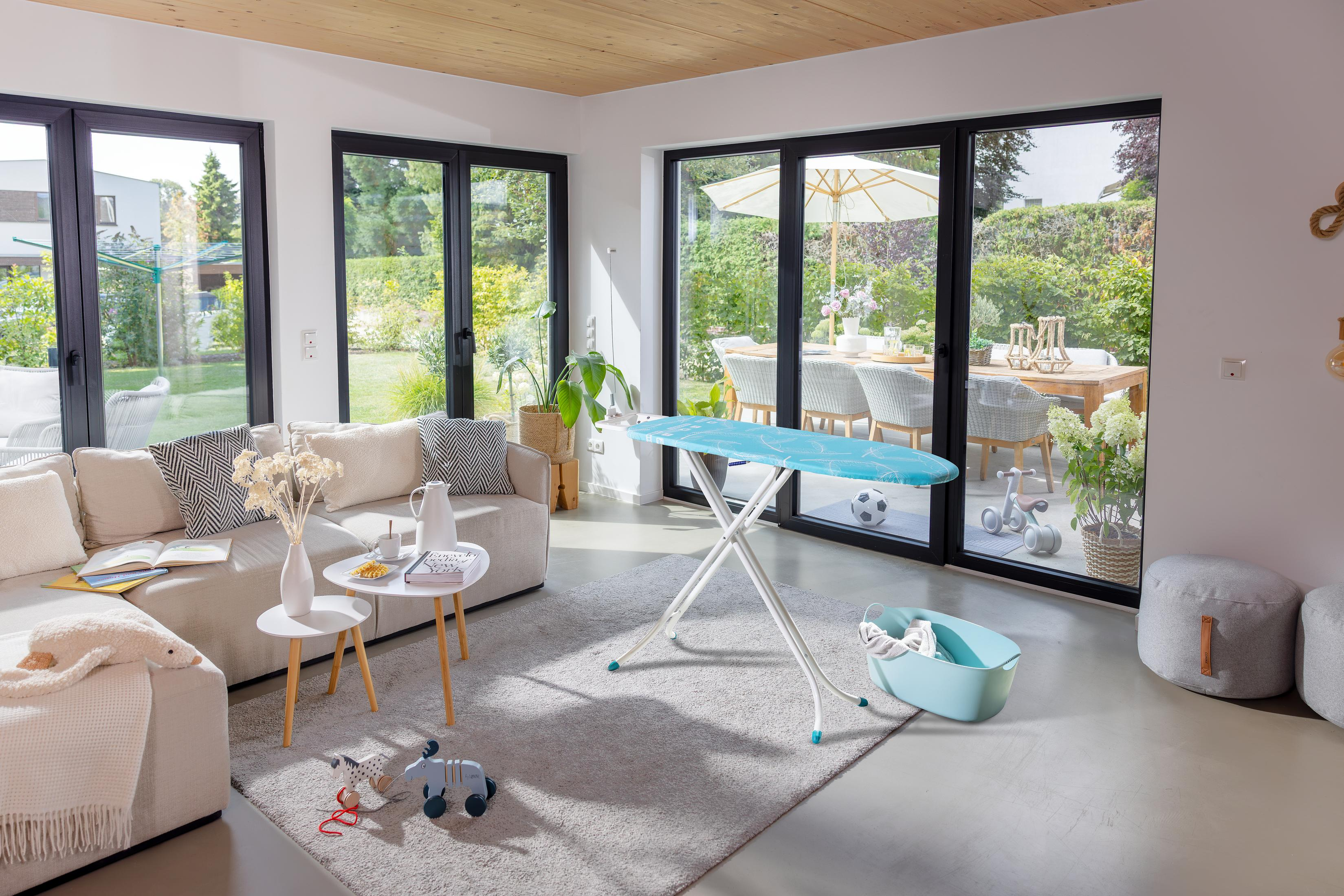 Ein Wohnzimmer mit Blick auf eine Terrasse, mit Sofa, Bügelbrett und Spielzeug.