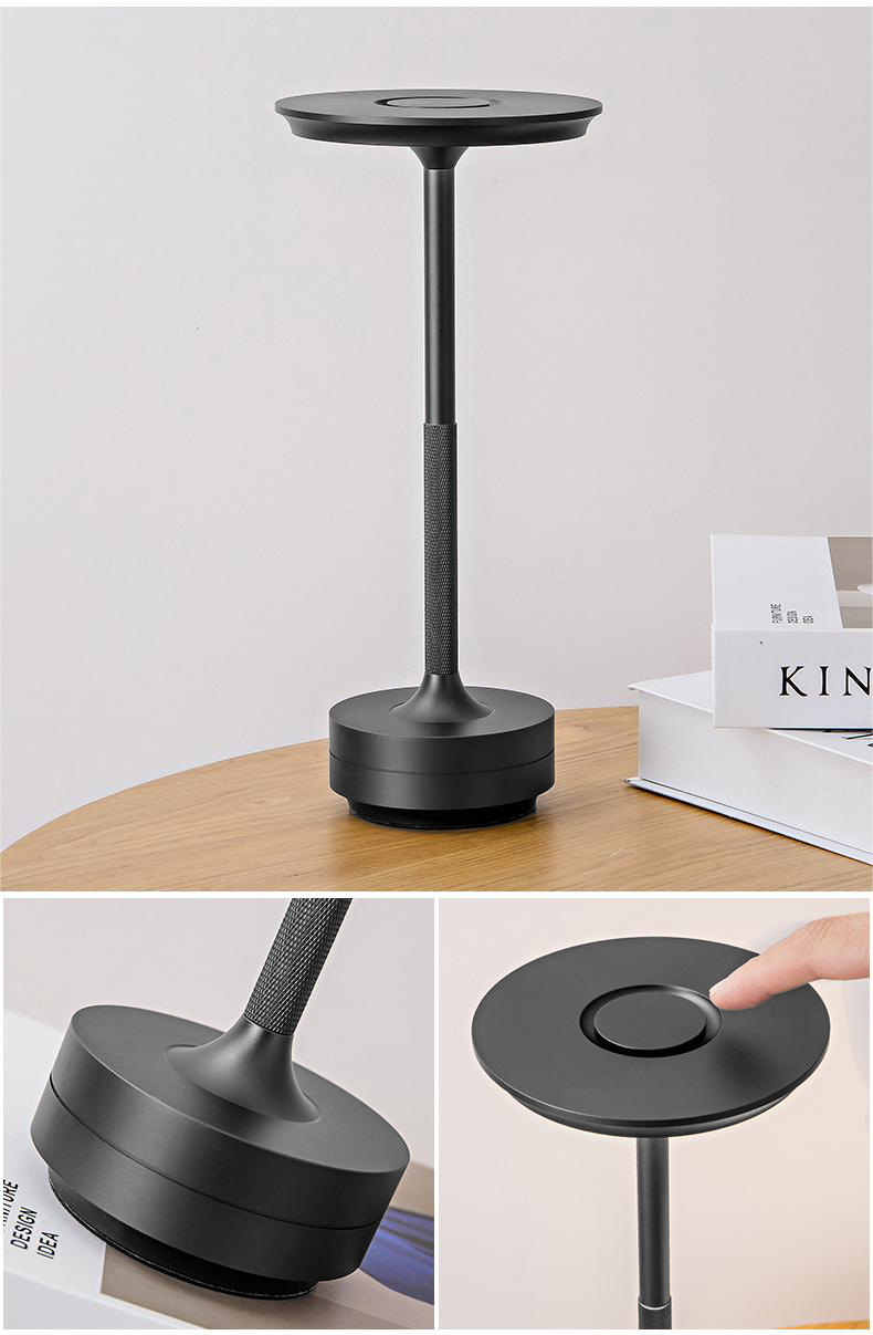 Eine schwarze Schreibtischlampe auf einem Holztisch mit Büchern daneben.