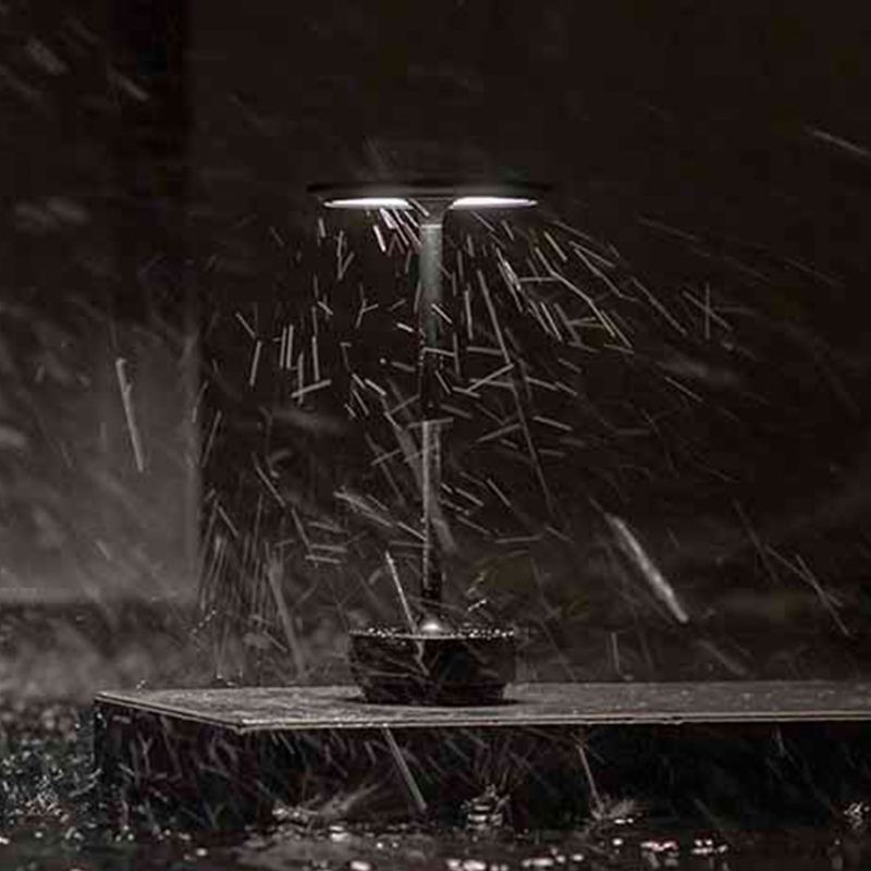 Eine Lampe im Regen auf einer dunklen Plattform.
