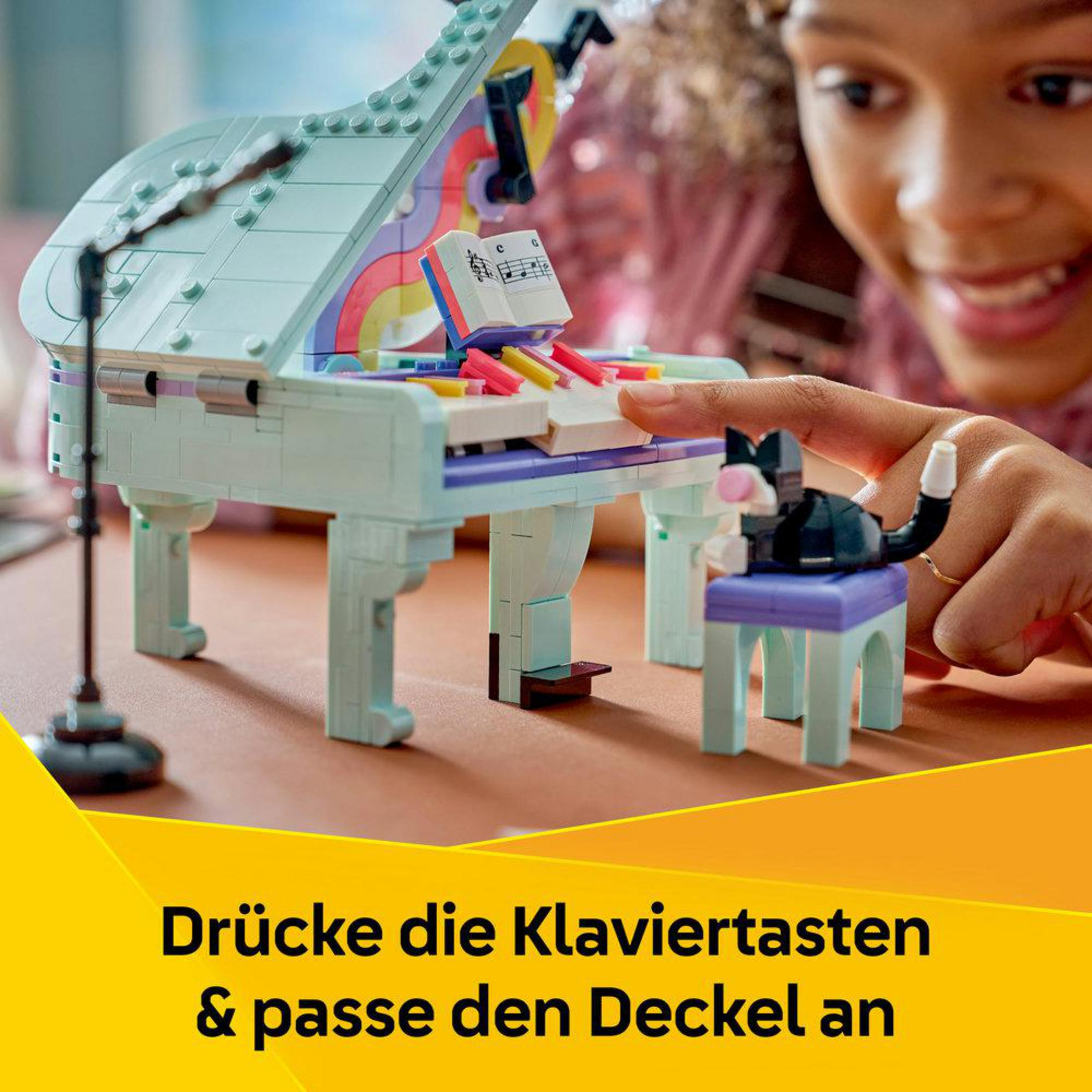 Un niño juega con un piano de Lego con partituras y un gato.