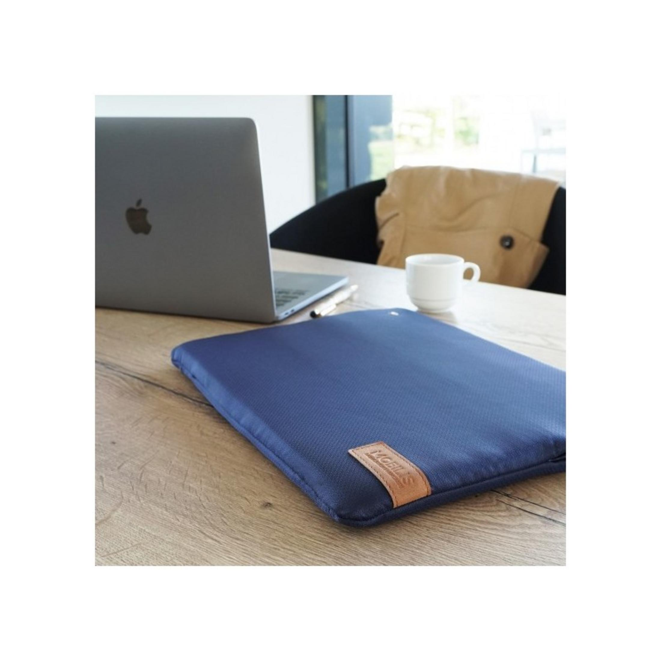 Una custodia blu scuro per laptop su un tavolo di legno accanto a un laptop, tazza e penna.