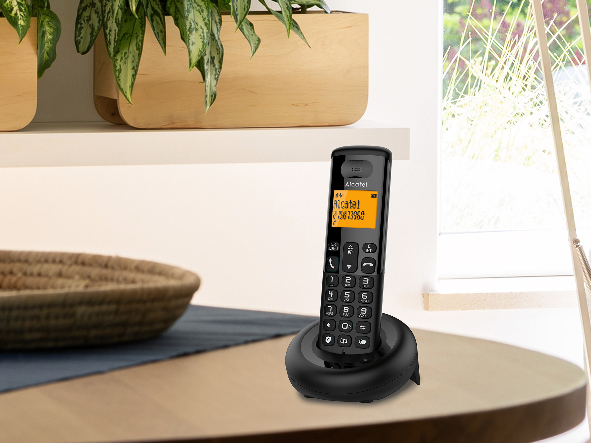Un telefono cordless nero Alcatel sulla sua base di ricarica.