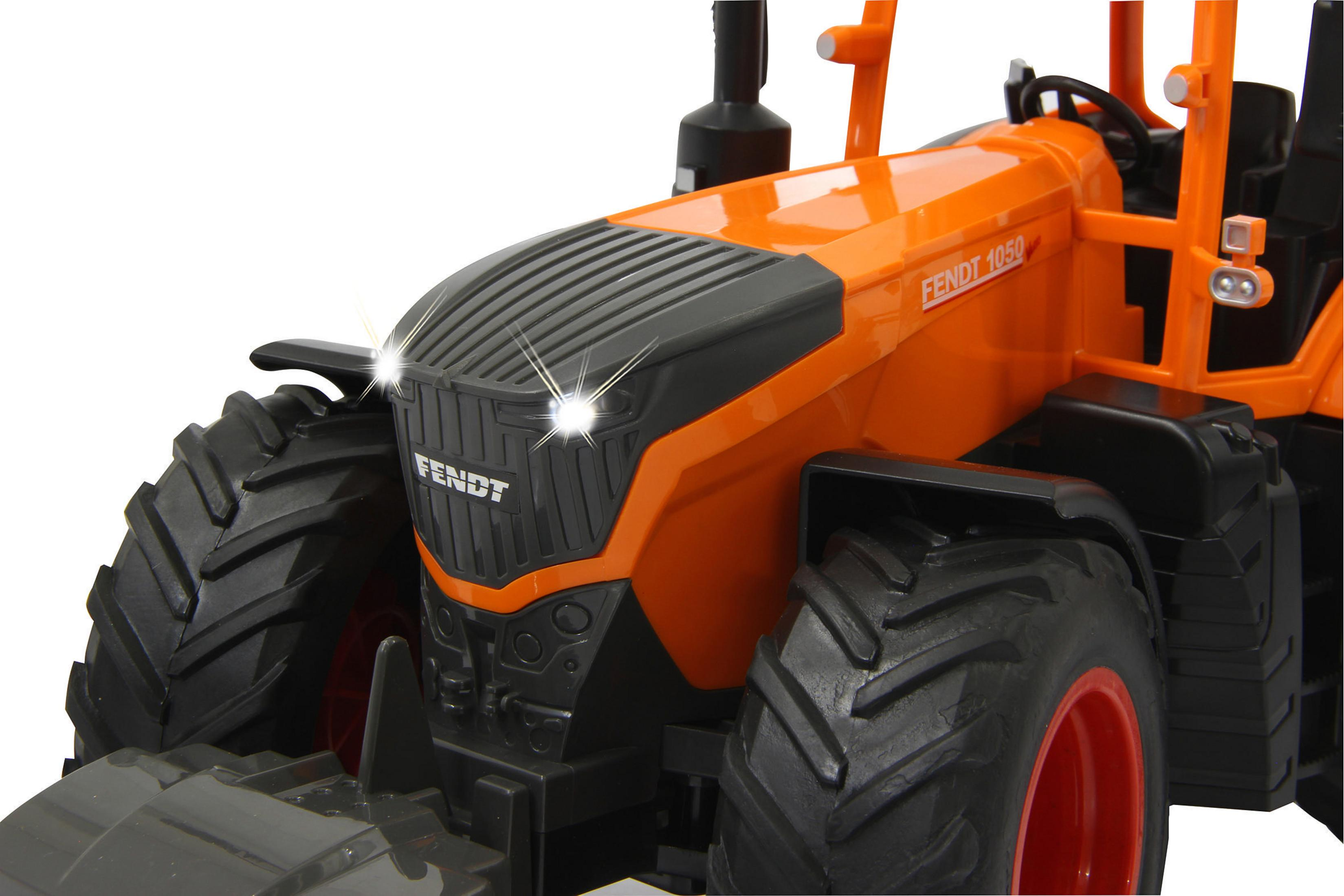 Un tractor Fendt 1050 naranja con grandes ruedas y luces encendidas.