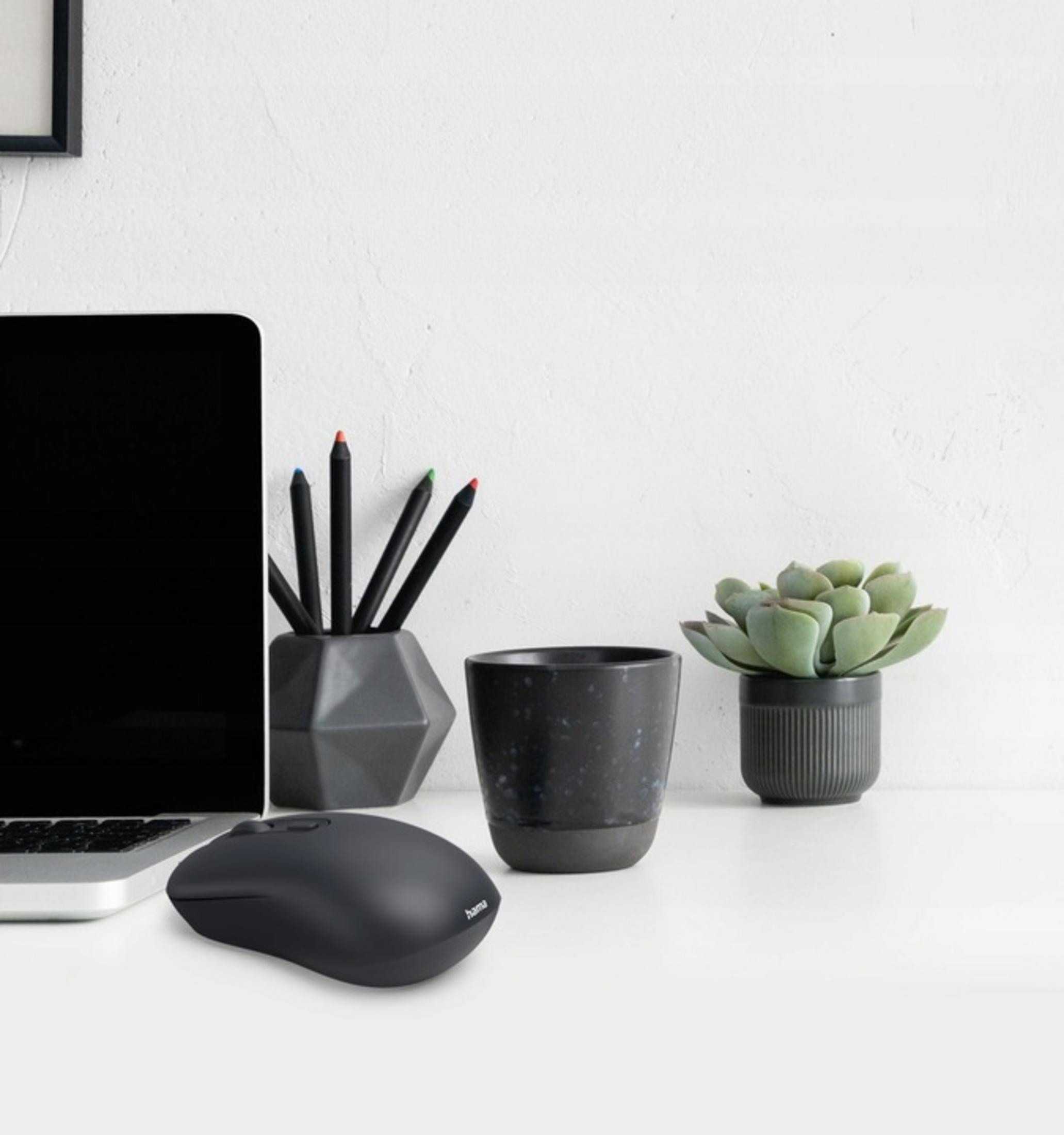 Un laptop nero, mouse, portapenne con penne, tazza e pianta su una scrivania.