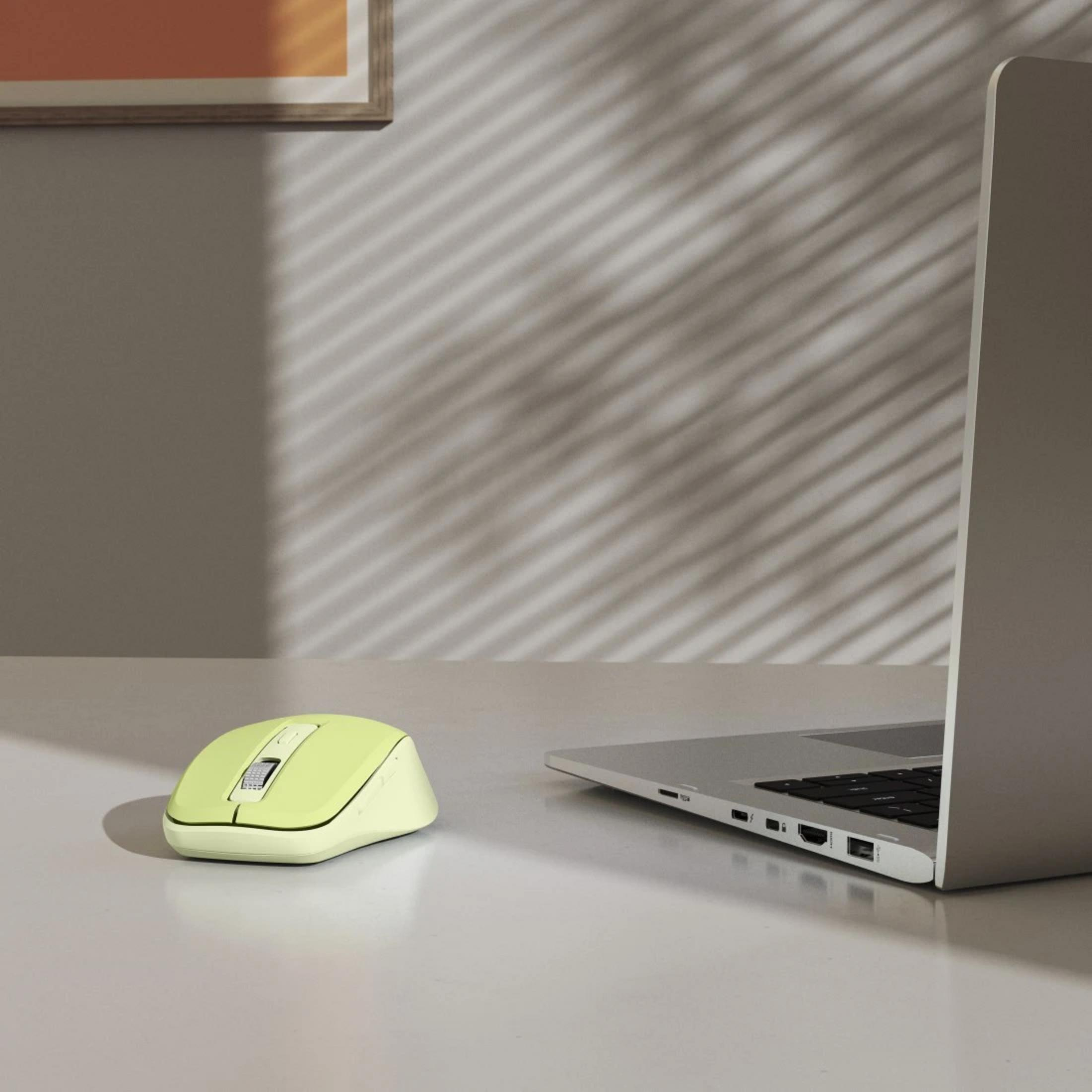 Un mouse verde chiaro e un laptop su un tavolo. Luce filtra attraverso le persiane.