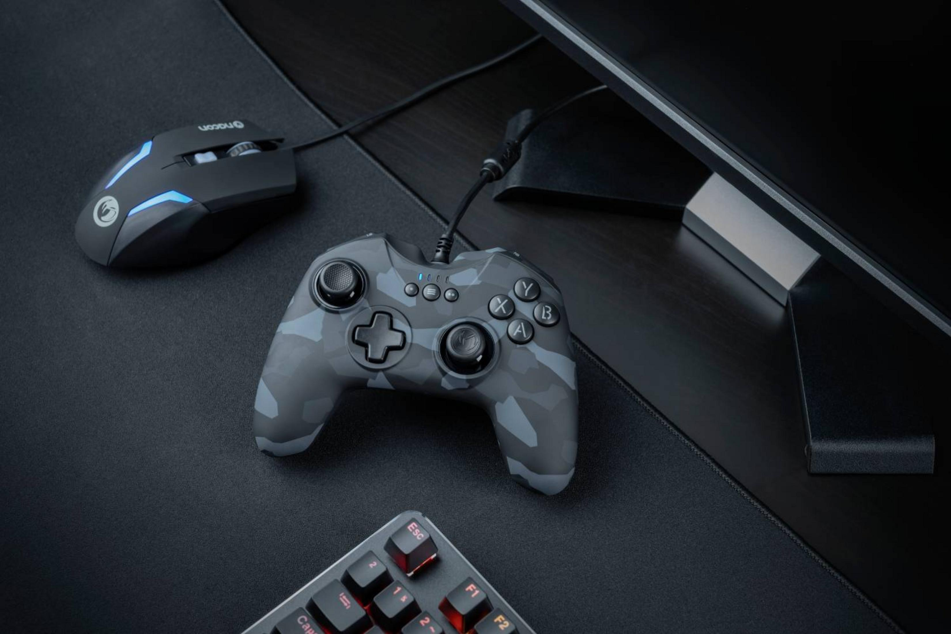 Controller mimetico grigio, mouse nero con luci blu e tastiera su tappetino nero.