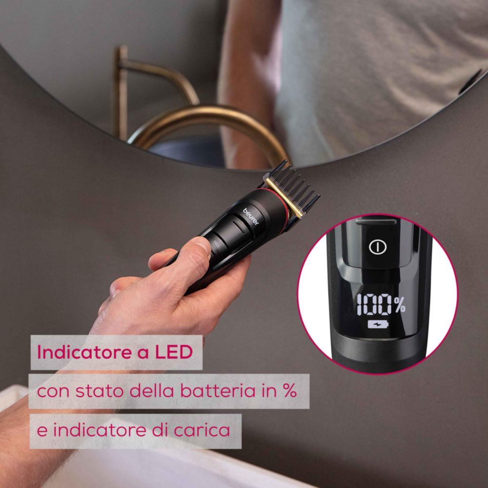 Un homme tient une tondeuse noire avec écran LED indiquant 100% de batterie.