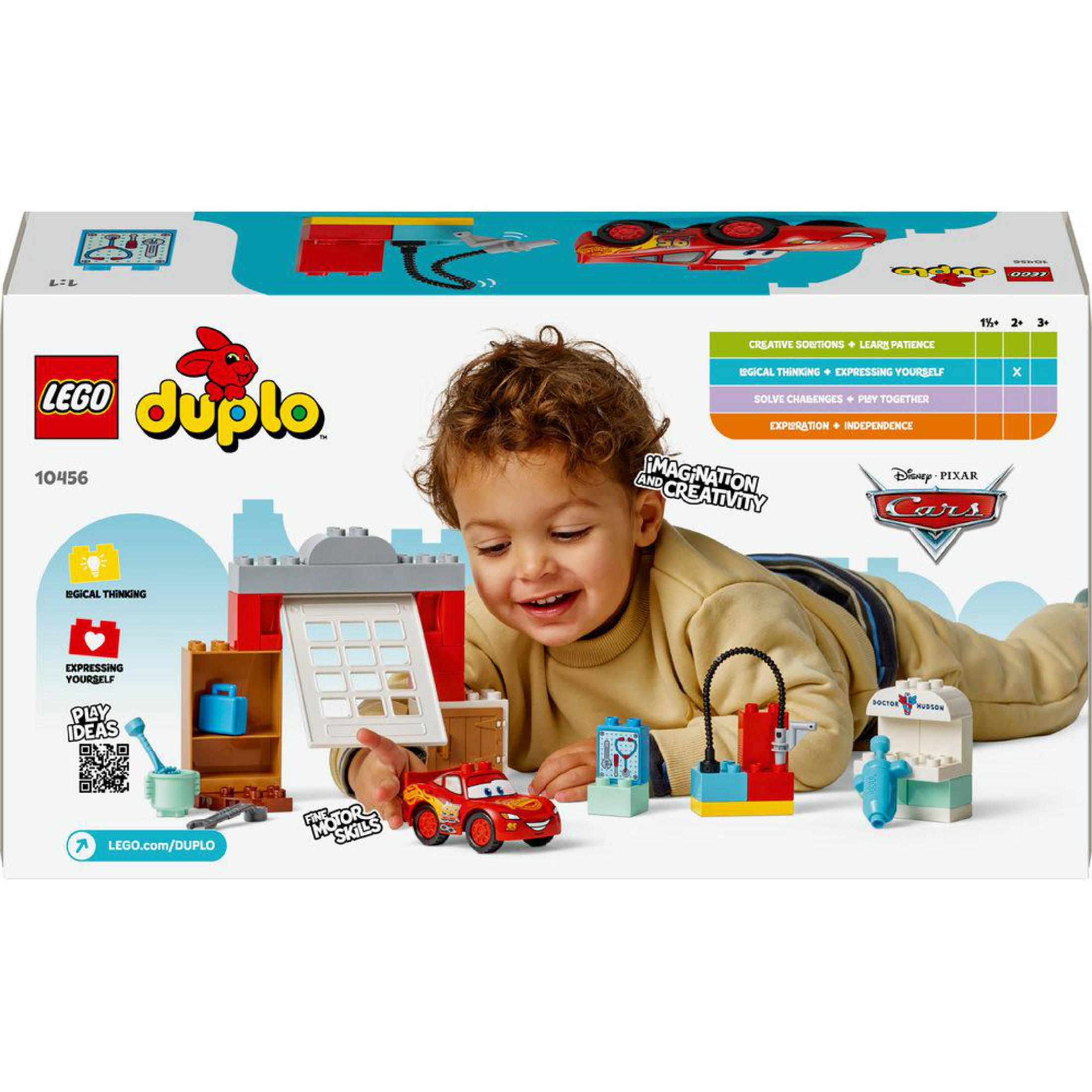 Un niño pequeño juega con un set de Lego Duplo Cars con Rayo McQueen y un taller.