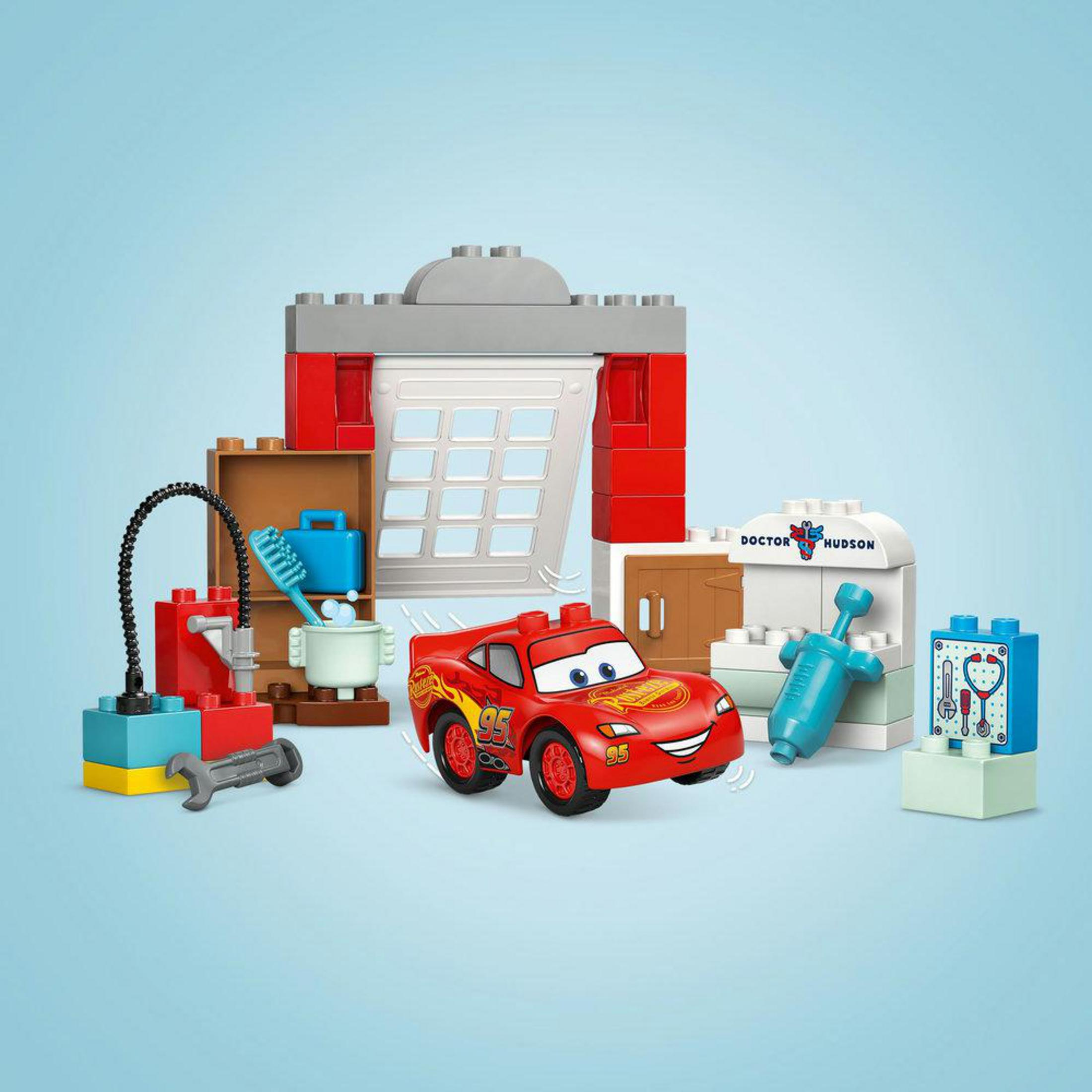 Un coche rojo de Lego con accesorios de taller y médico sobre fondo azul.