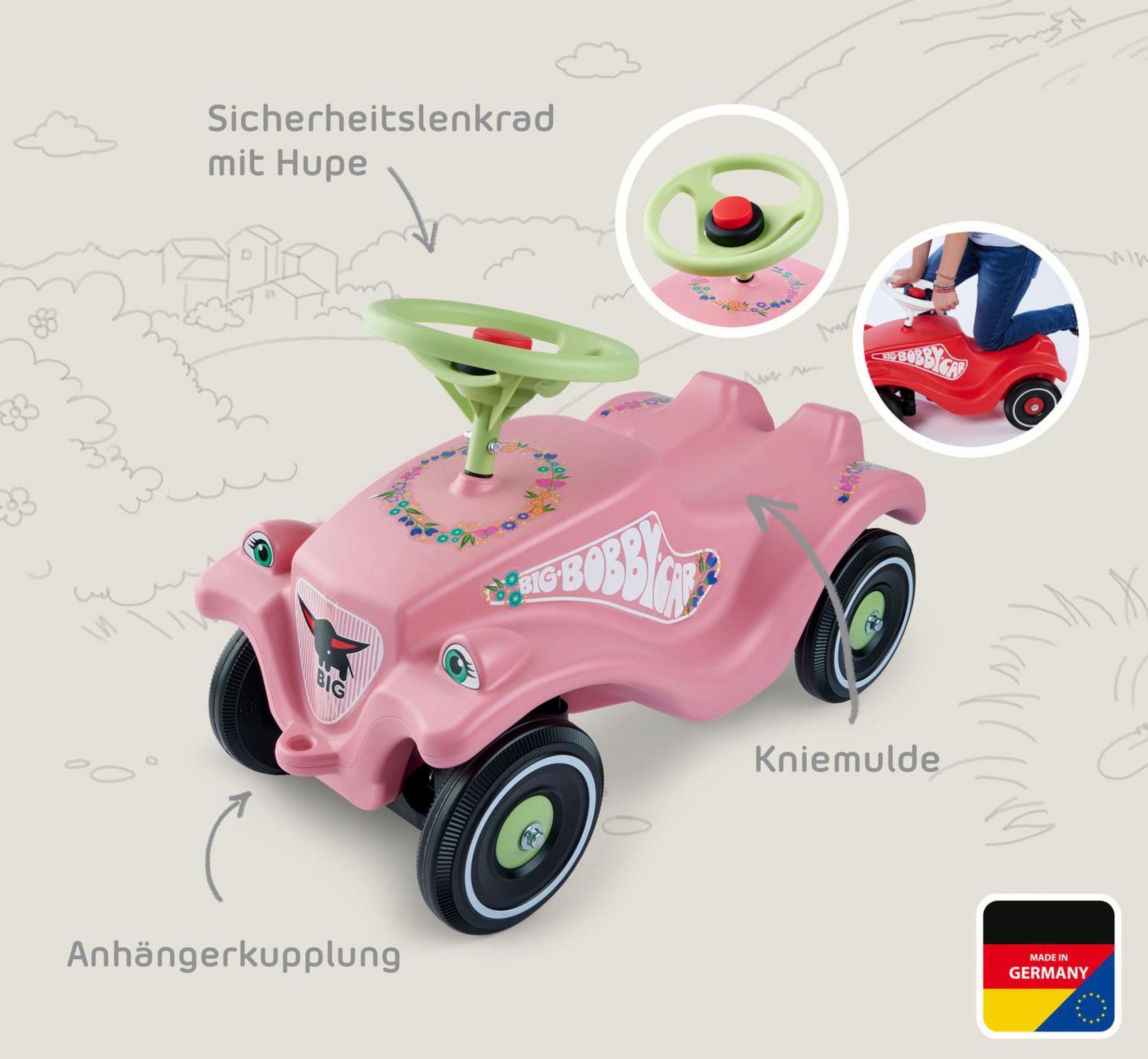 Ein rosafarbener Bobby-Car mit grünen Elementen, Hupenlenkrad und Aufklebern.