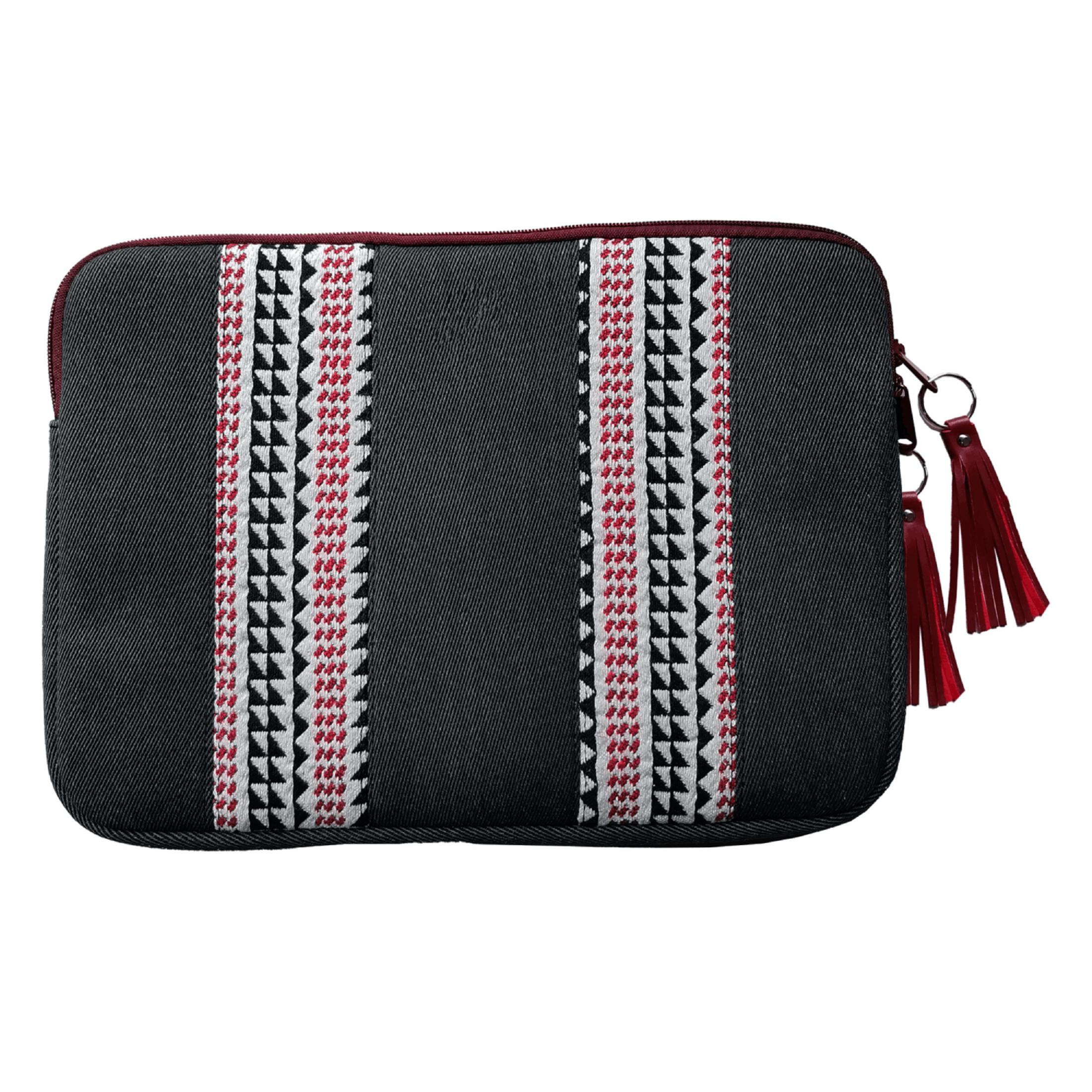 Bolso negro con patrones geométricos rojos y blancos y borlas.