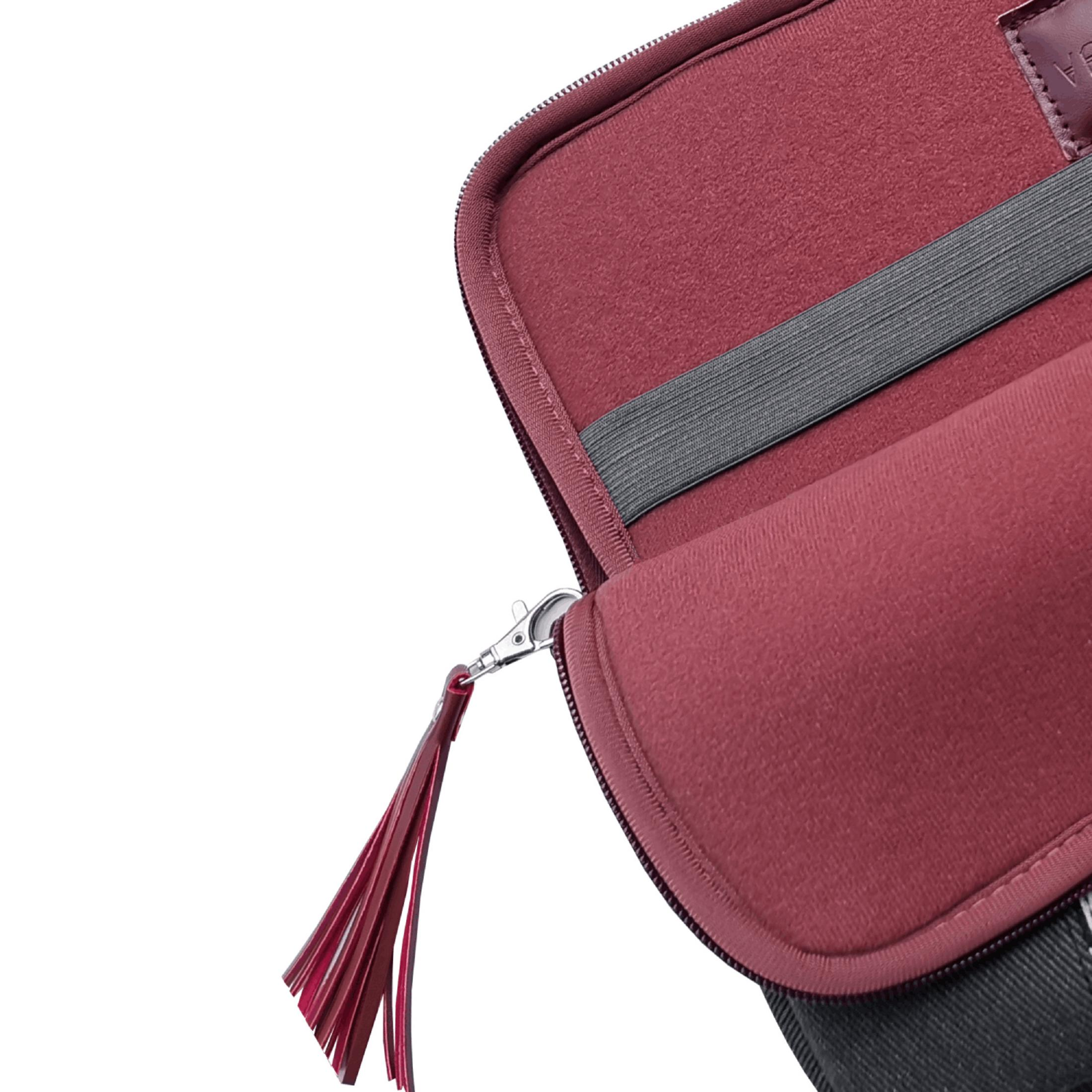 Bolsa roja con cremallera, charm de borla y correa elástica.