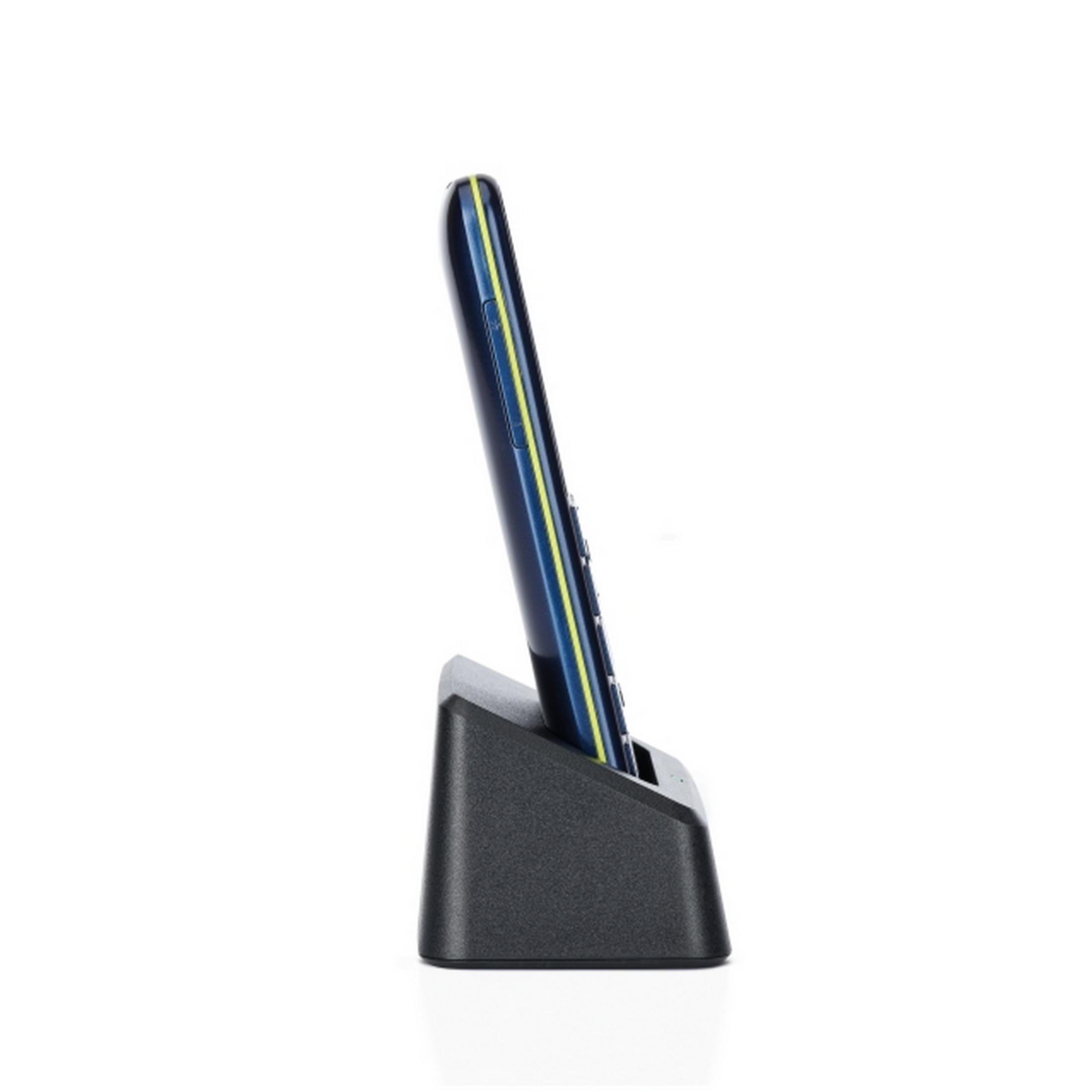 Un teléfono móvil azul con rayas amarillas está en una base de carga negra.