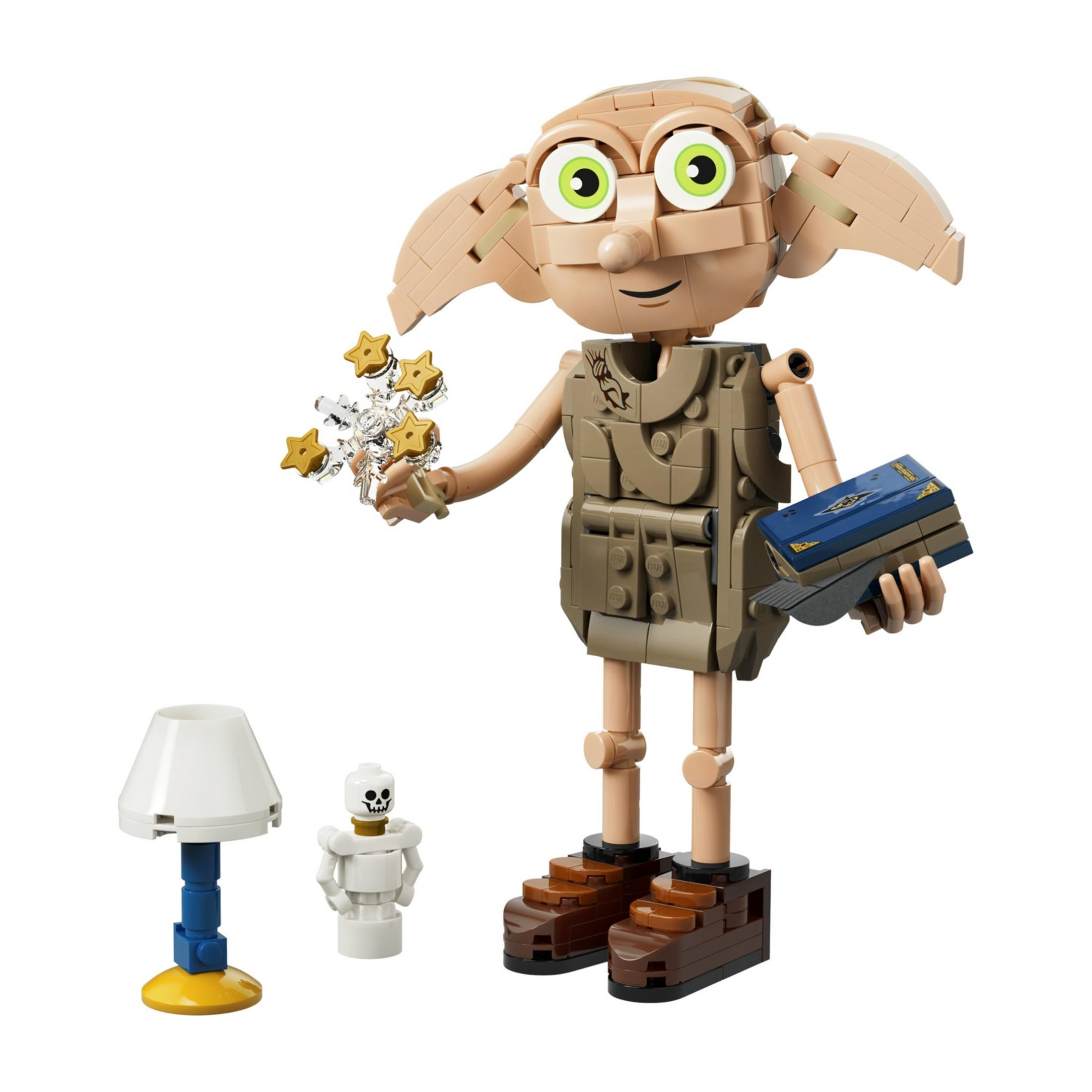 Lego Dobby trzyma gwiazdy i książkę. Obok stoją lampa i szkielet.