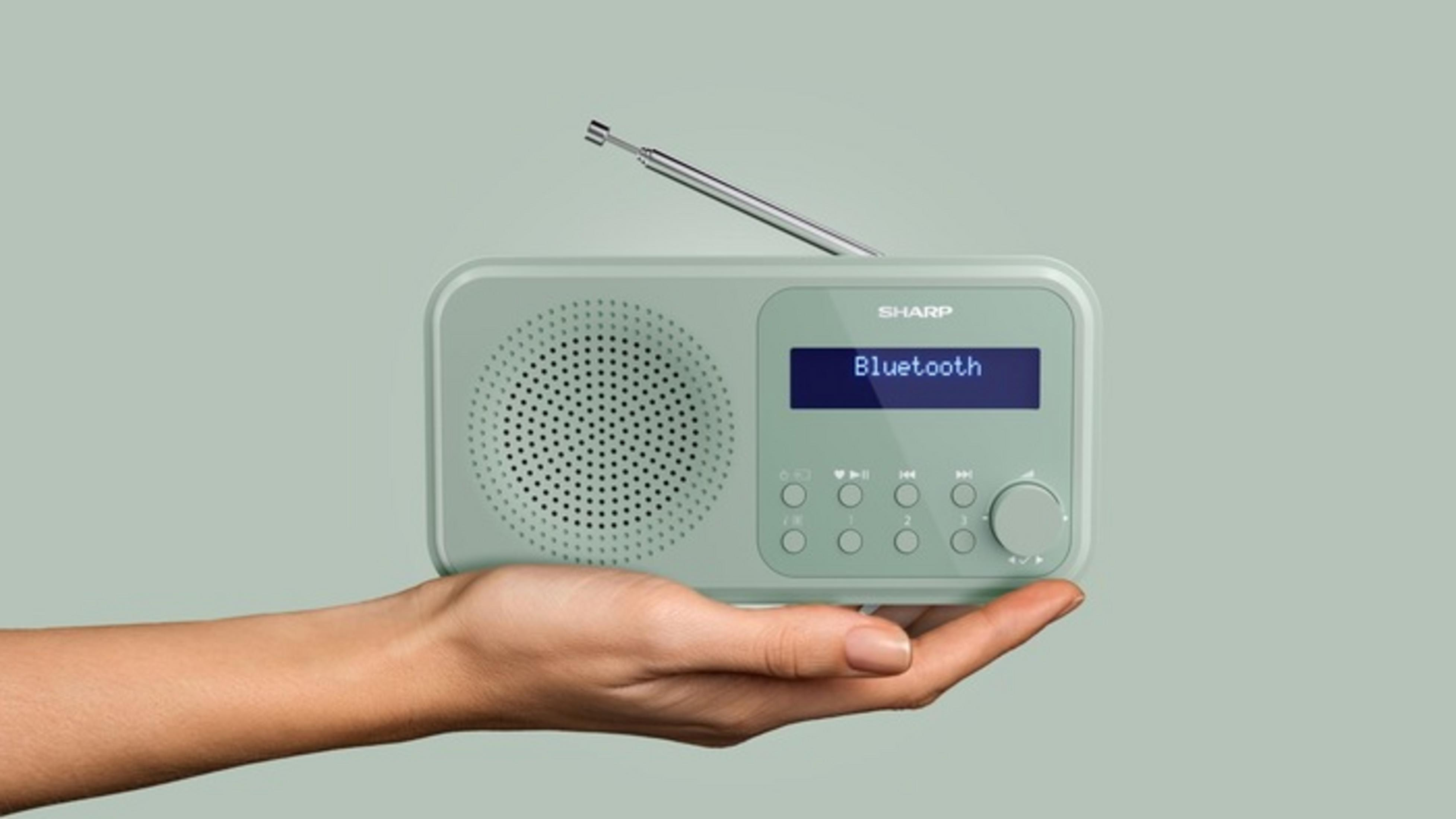 Eine Hand hält ein hellgrünes Sharp Radio mit ausgefahrenem Antennenstab und Bluetooth-Anzeige.
