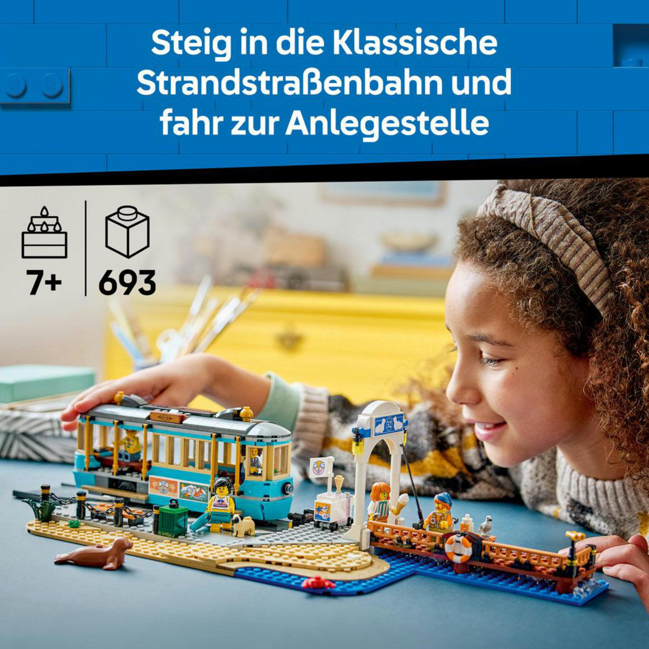 Un niño construye un tranvía LEGO en el muelle con figuras y una foca.