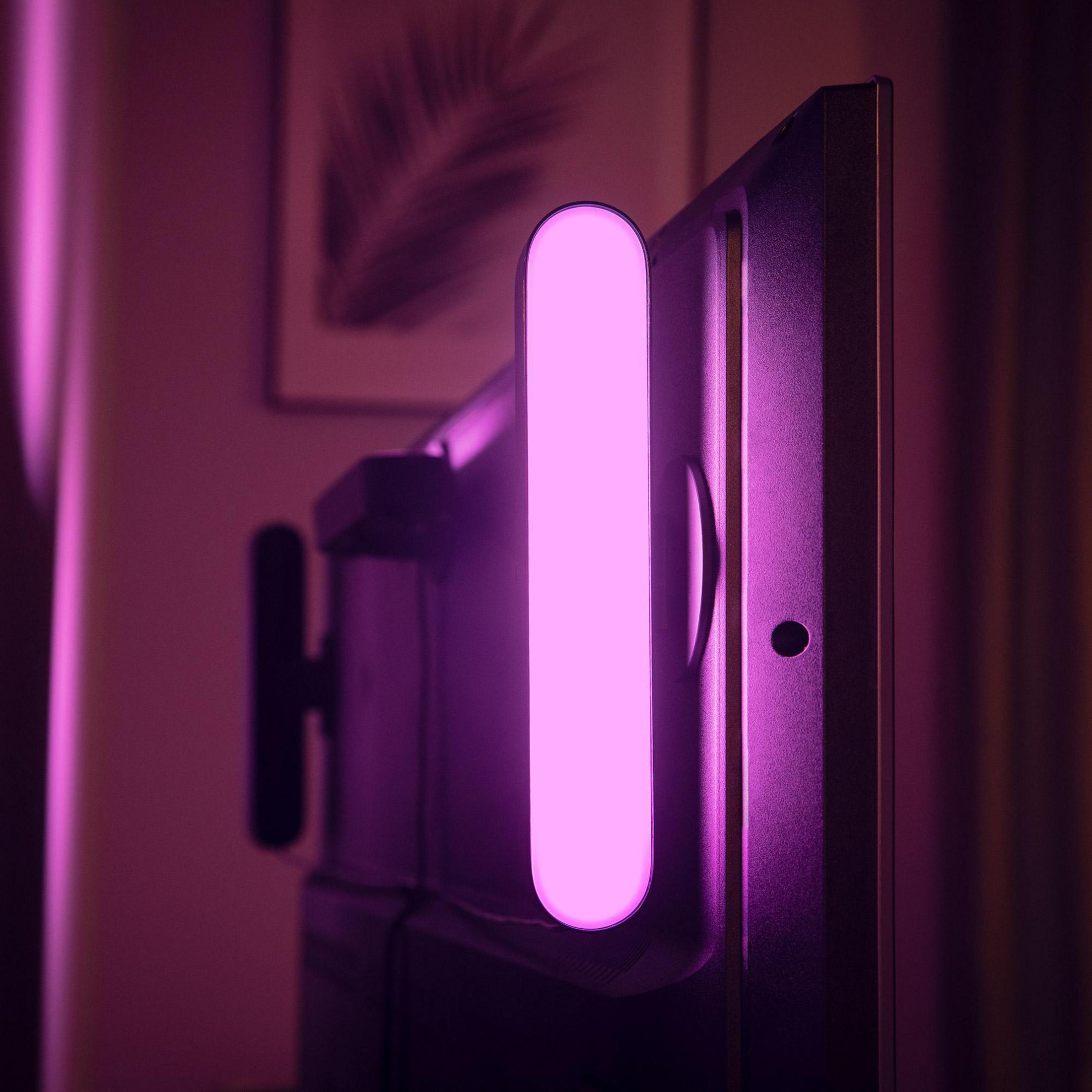 Una striscia di luce rosa illumina il retro di un televisore.