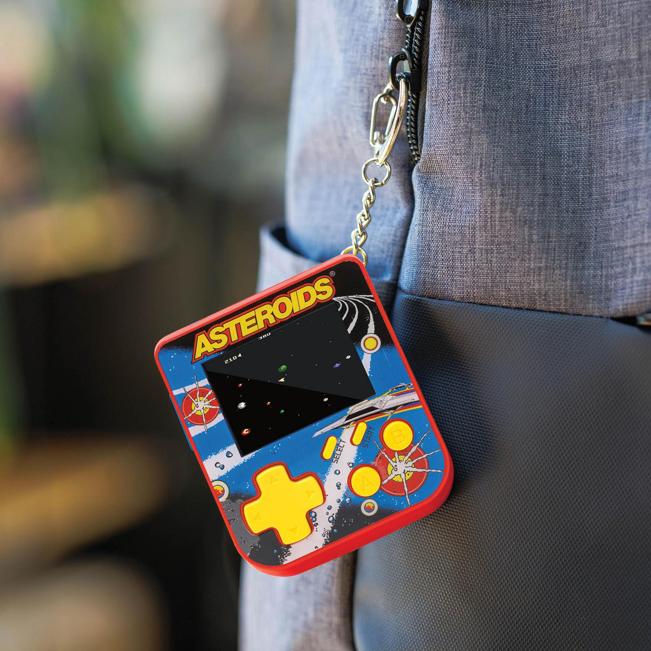 Un juego portátil de Asteroids con botones rojos y azules cuelga de una bolsa.