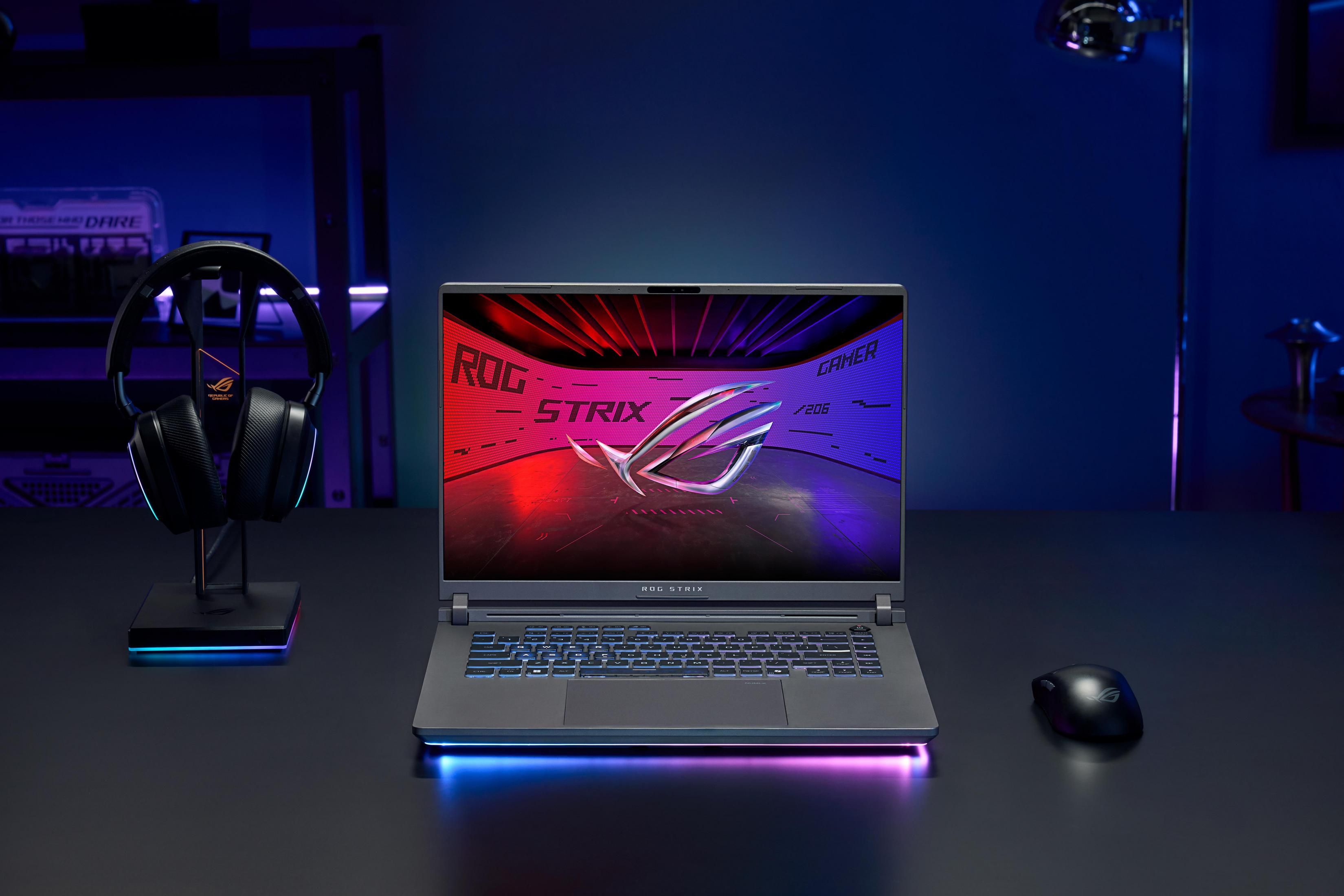 Laptop gamingowy ROG Strix z podświetleniem RGB, słuchawkami i myszką na biurku.