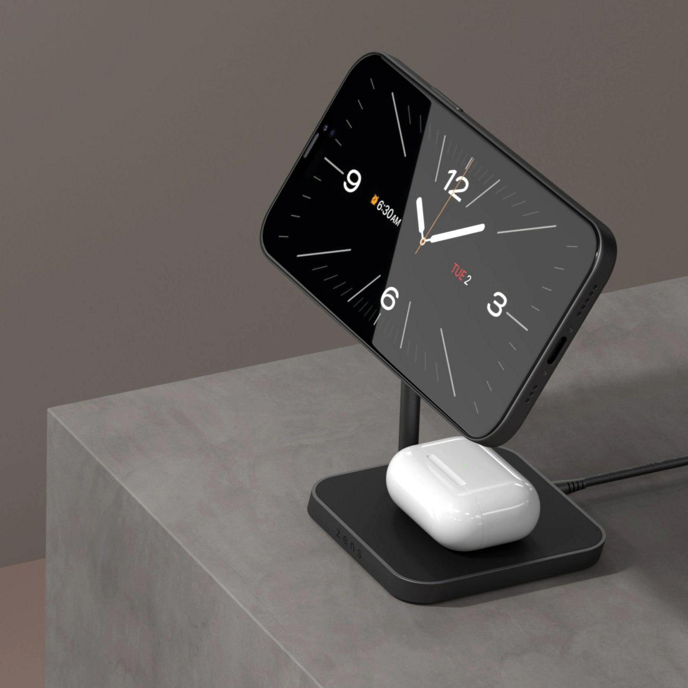 Ein Smartphone mit einer Uhr und ein weißes Ladeetui auf einer Ladestation.