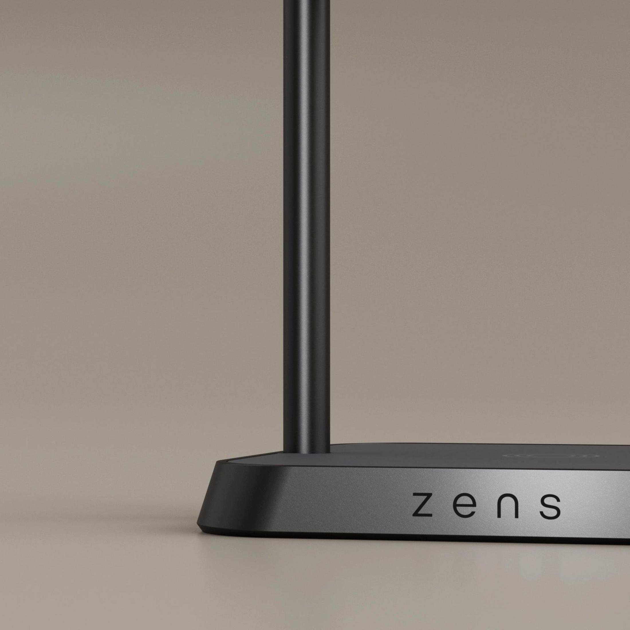 Schwarzer Lampenfuß mit dem Logo "zens" auf einem graubraunen Hintergrund.
