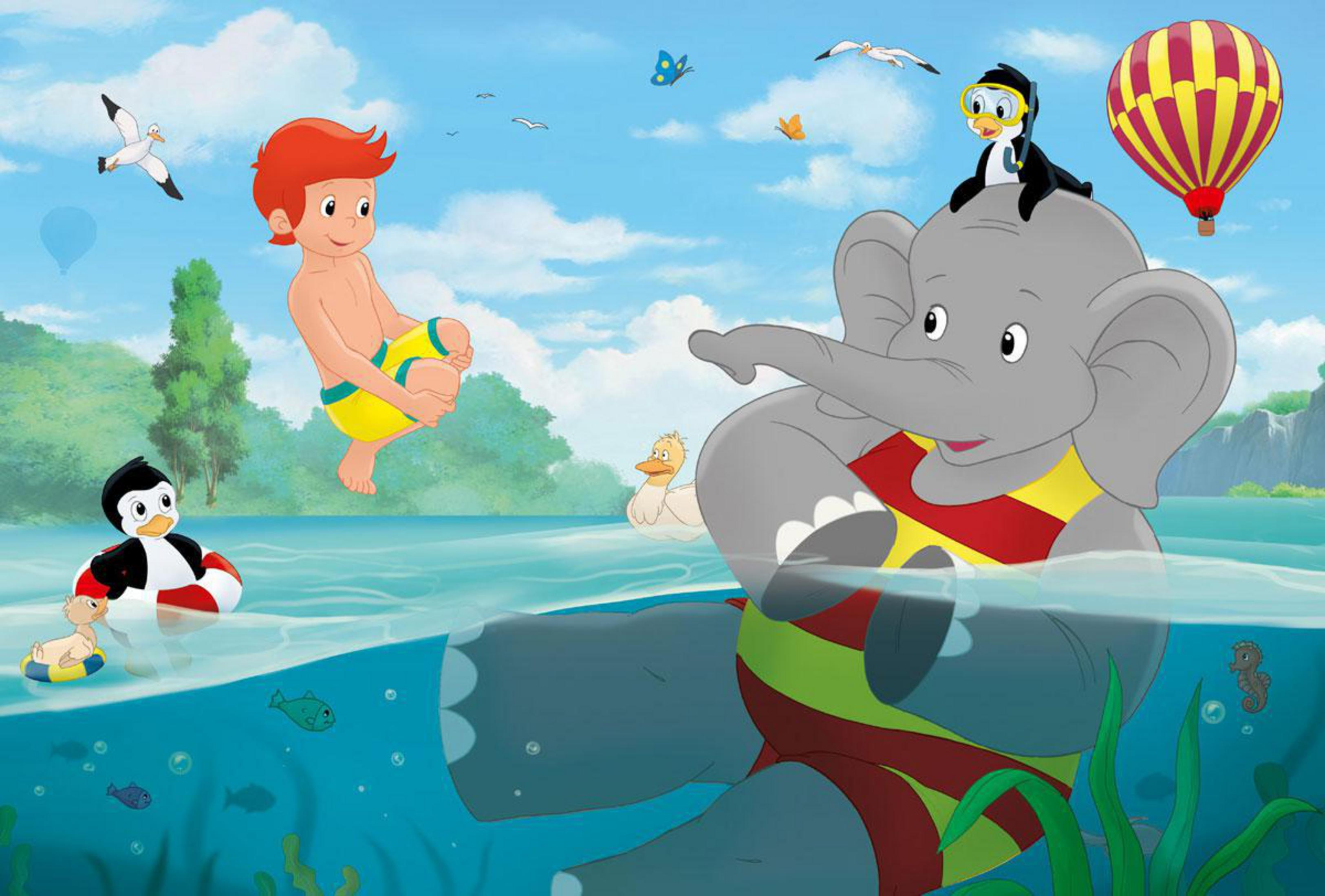 Un elefante con un pinguino in testa nell'acqua, un ragazzo e un pallone nelle vicinanze.