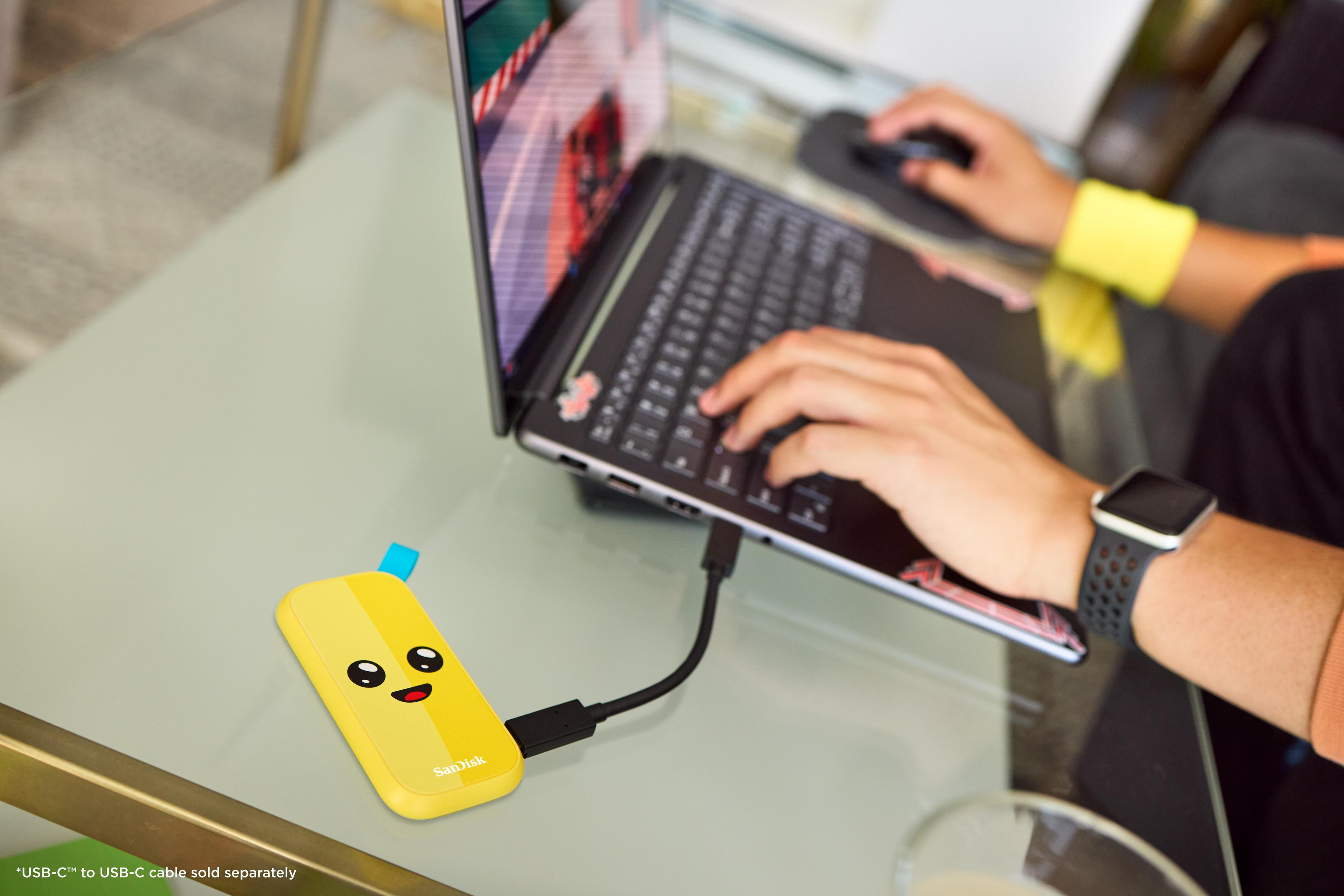 Un'unità SanDisk gialla con una faccia è collegata a un laptop.