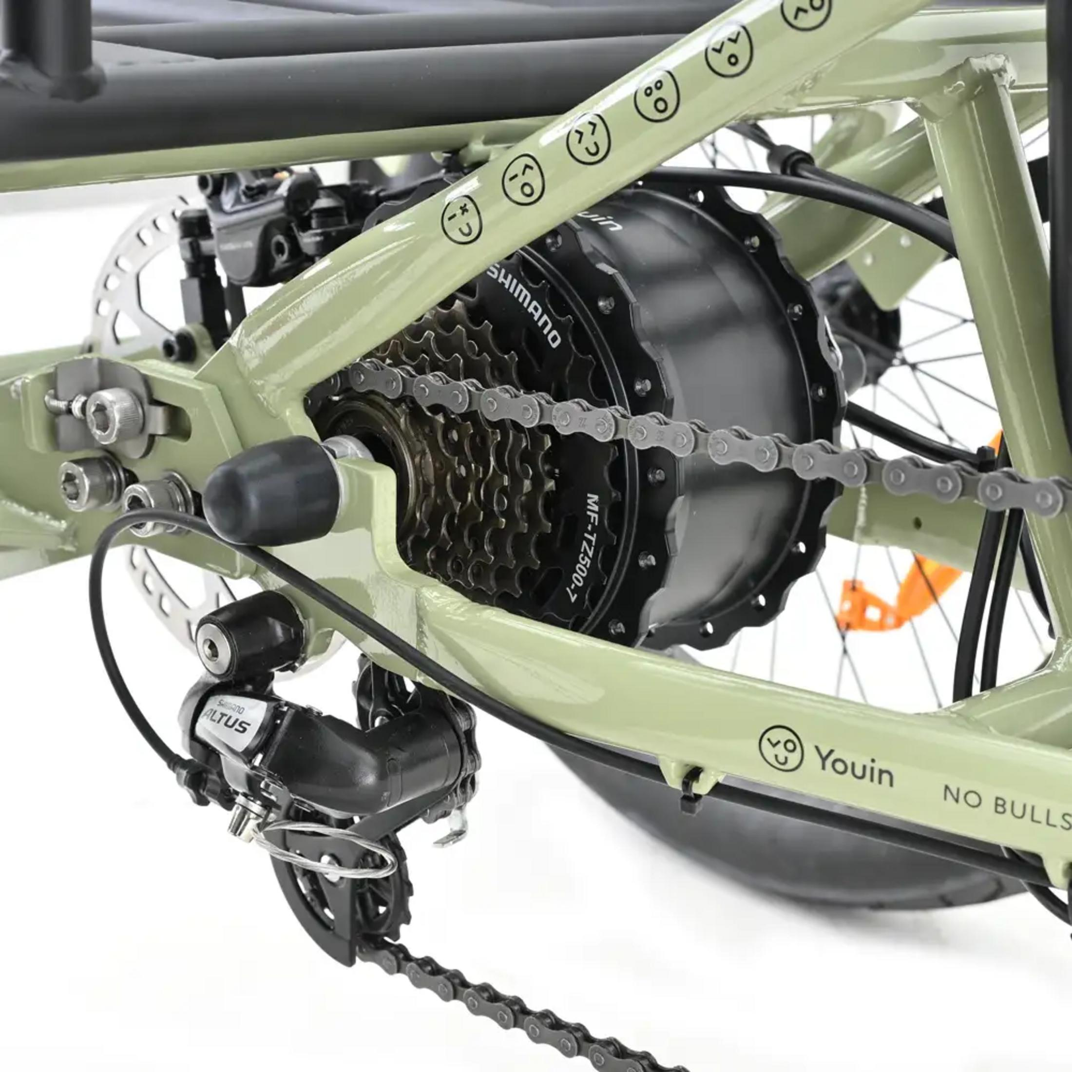 Primer plano de los engranajes de la bicicleta, cadena, desviador y motor. Color verde.