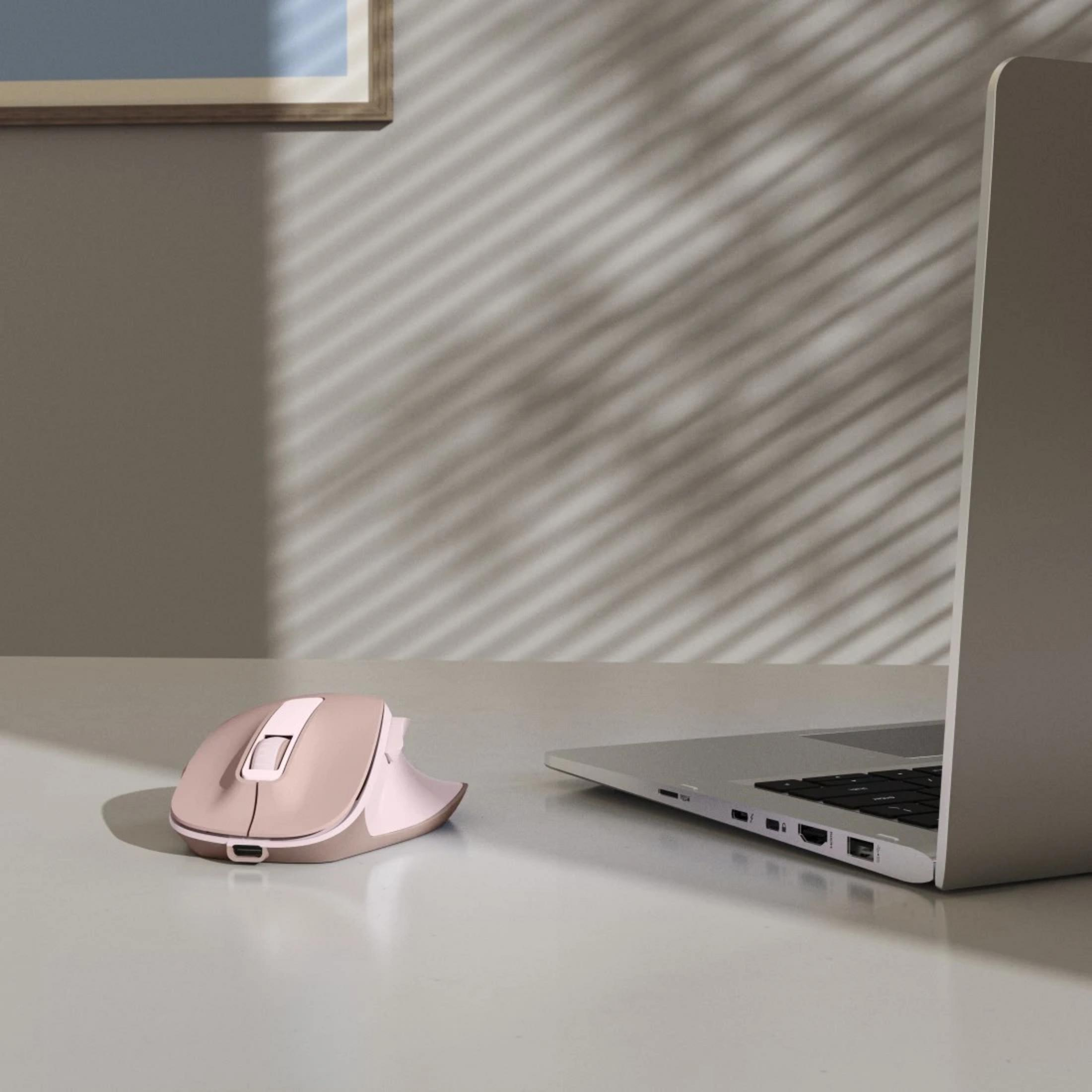 Ein rosafarbener Computer-Maus neben einem Laptop auf einem weißen Tisch.