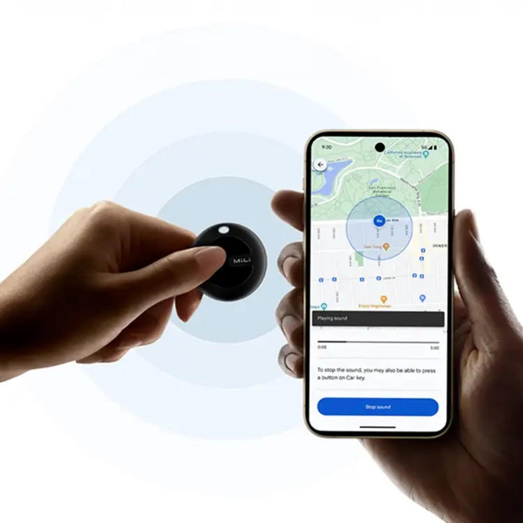 Eine Hand hält einen schwarzen Ortungschip. Daneben ein Smartphone zeigt eine Karte.