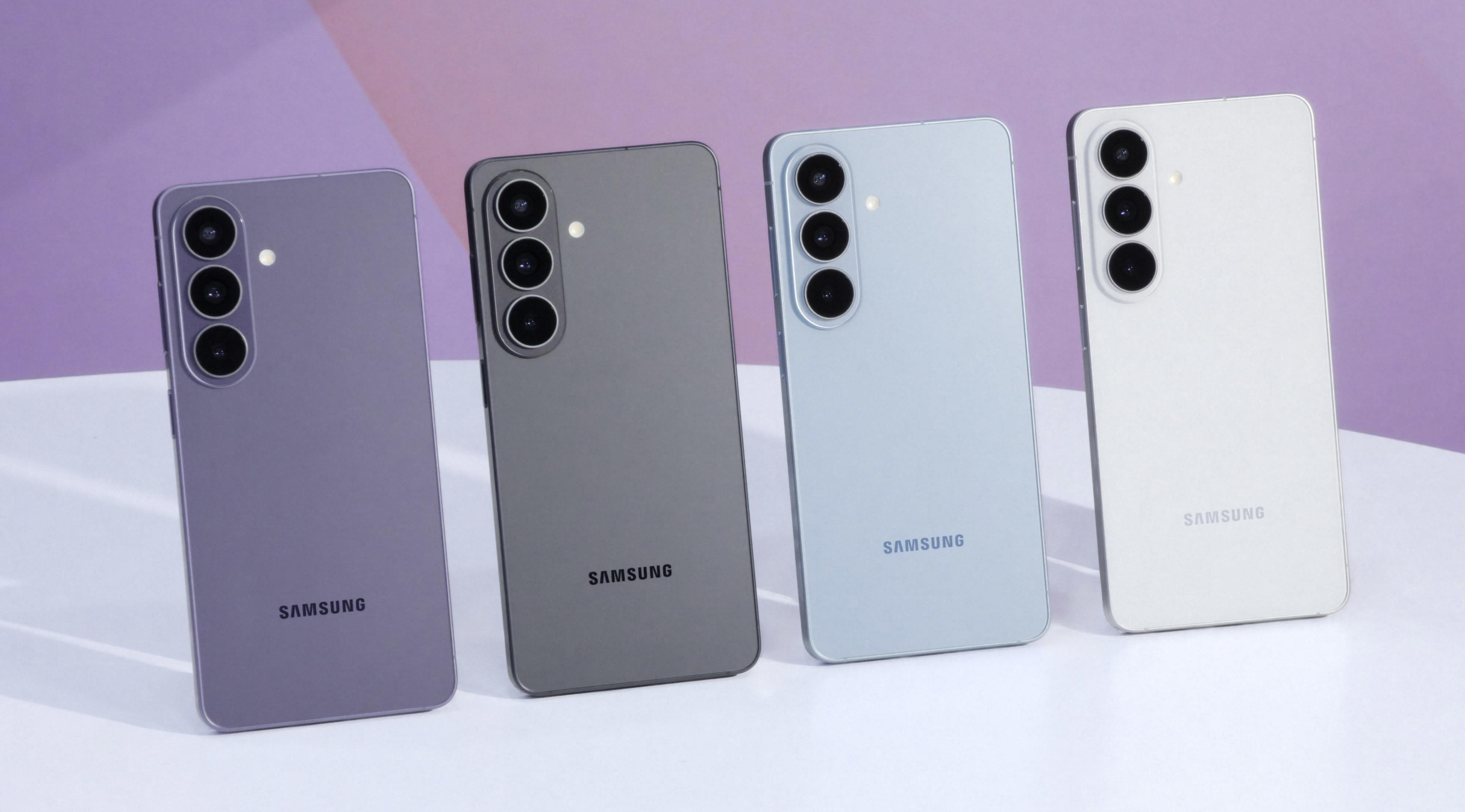 Vier Samsung Smartphones in Lila, Grau, Hellblau und Weiß auf einem weißen Tisch.