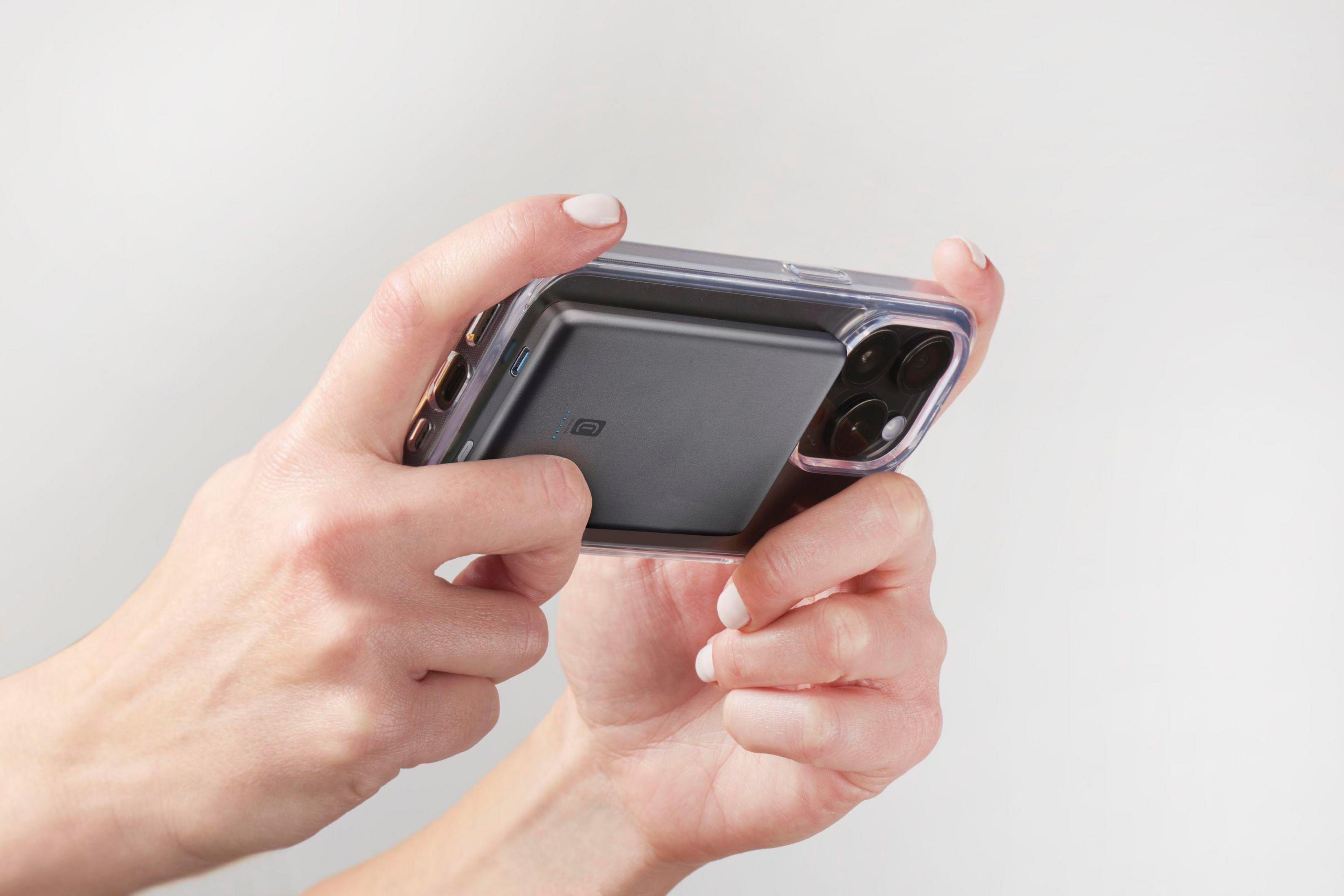 Mani che tengono uno smartphone in una custodia trasparente con batteria nera.